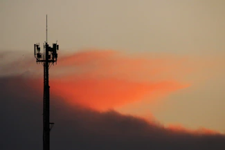 Cell tower silhouetted against a sunset sky
