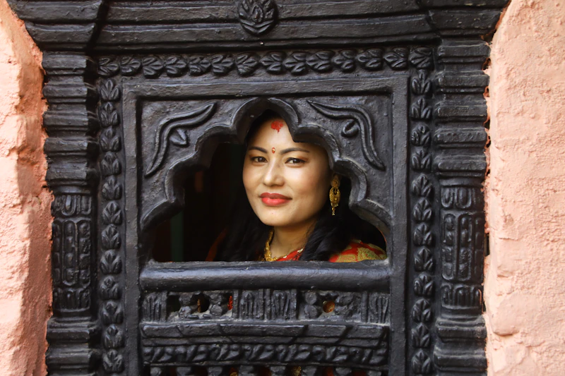 Indian woman peeking through a carved wooden window
