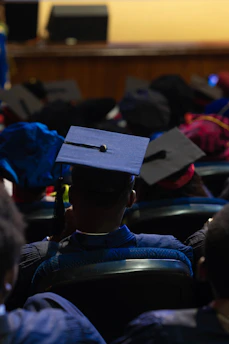 Graduates wearing caps and gowns in an auditorium.
