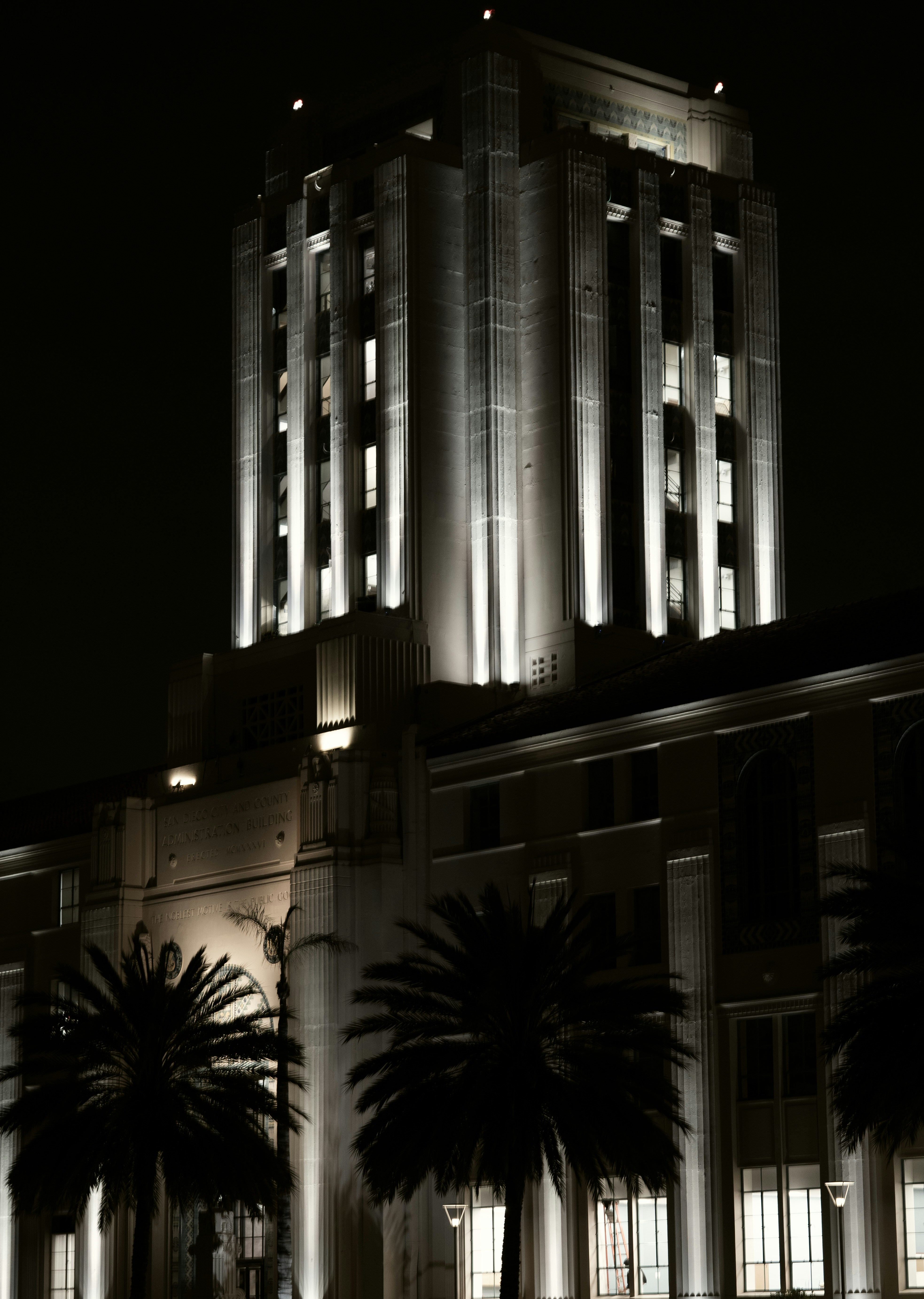 Bâtiment éclairé avec des palmiers la nuit