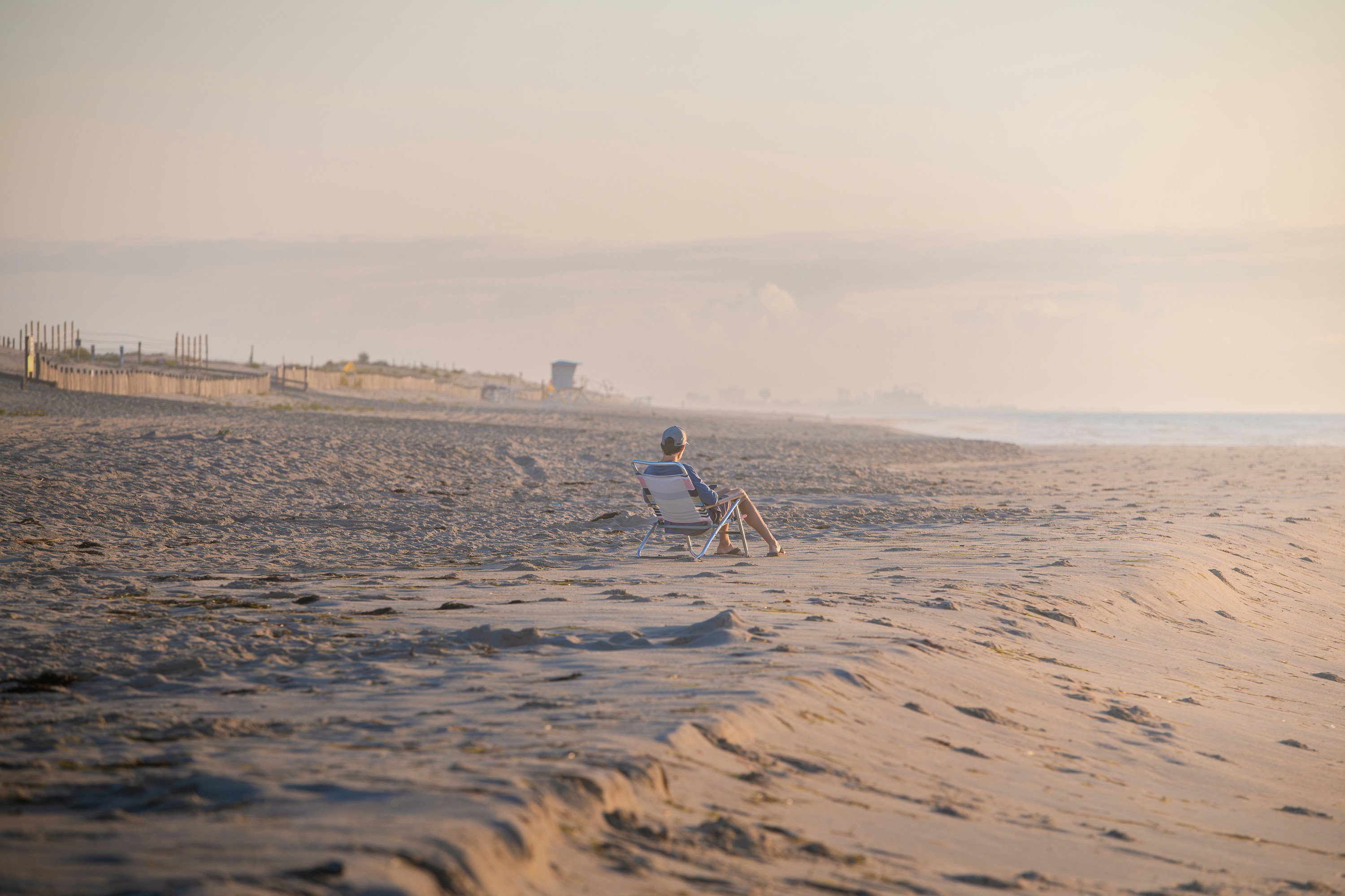 Person sitting on a beach chair overlooking the ocean.