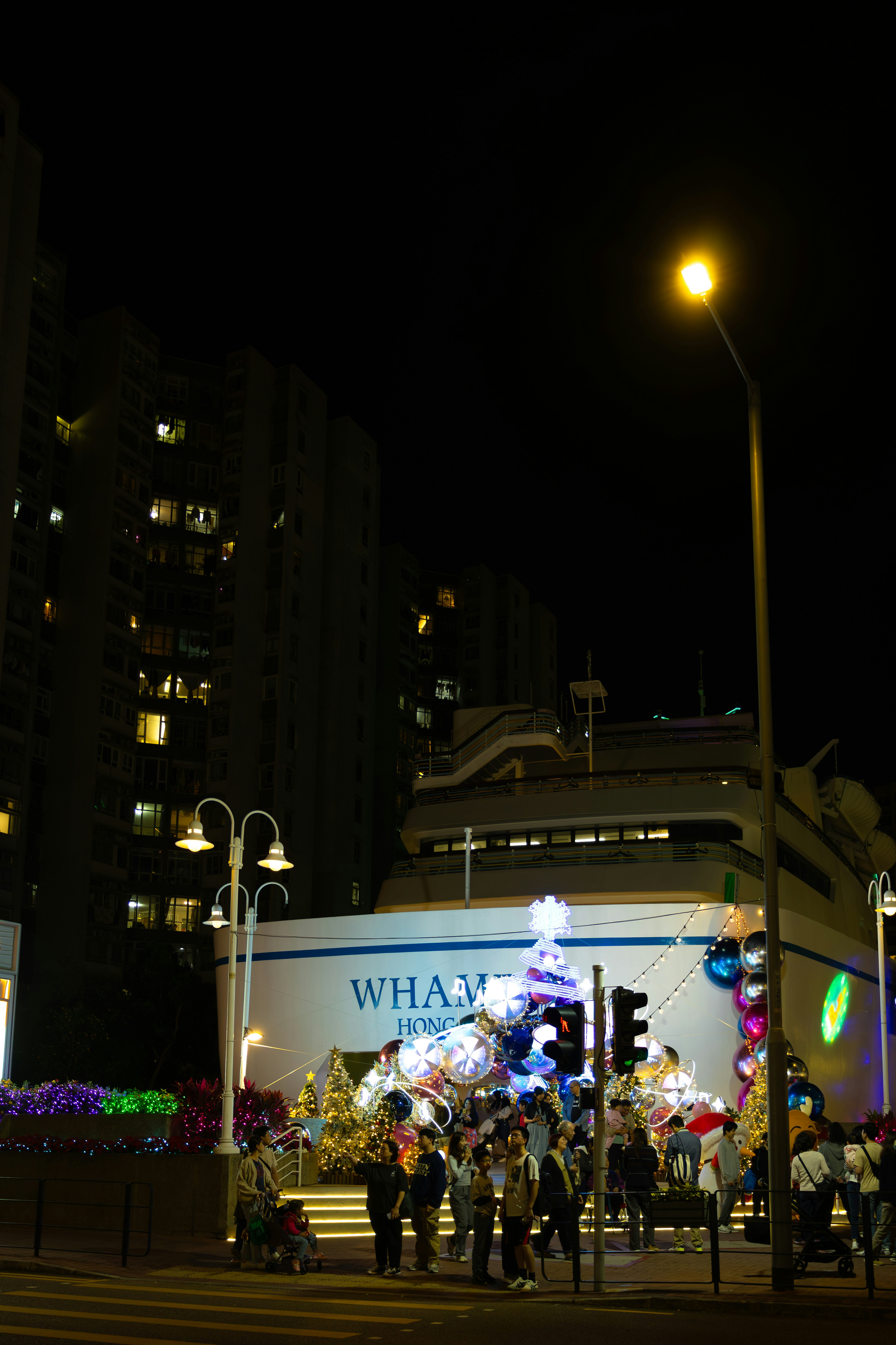 People gather around a decorated christmas tree at night.