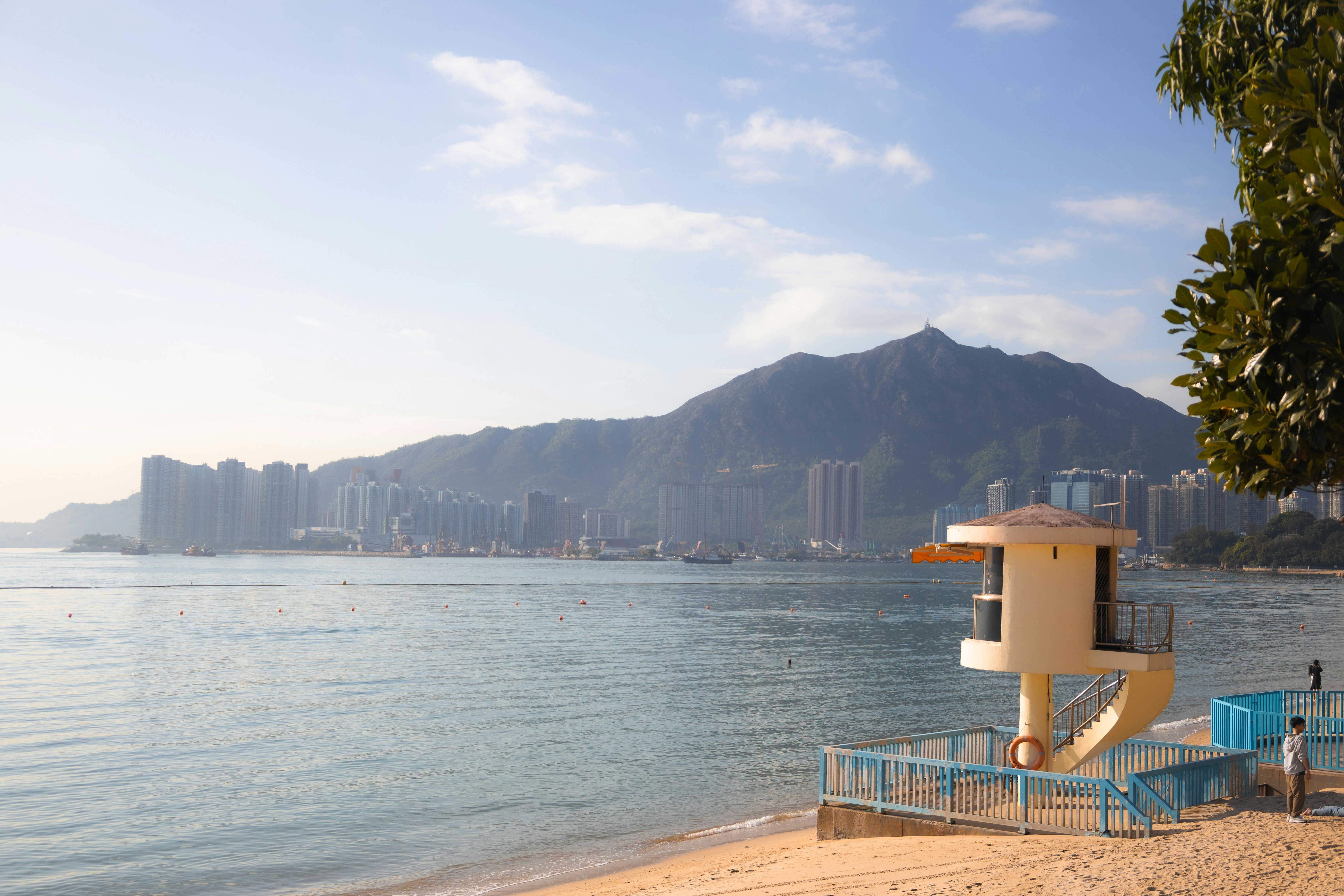 Estación de socorristas en una playa de arena con ciudad y montañas.