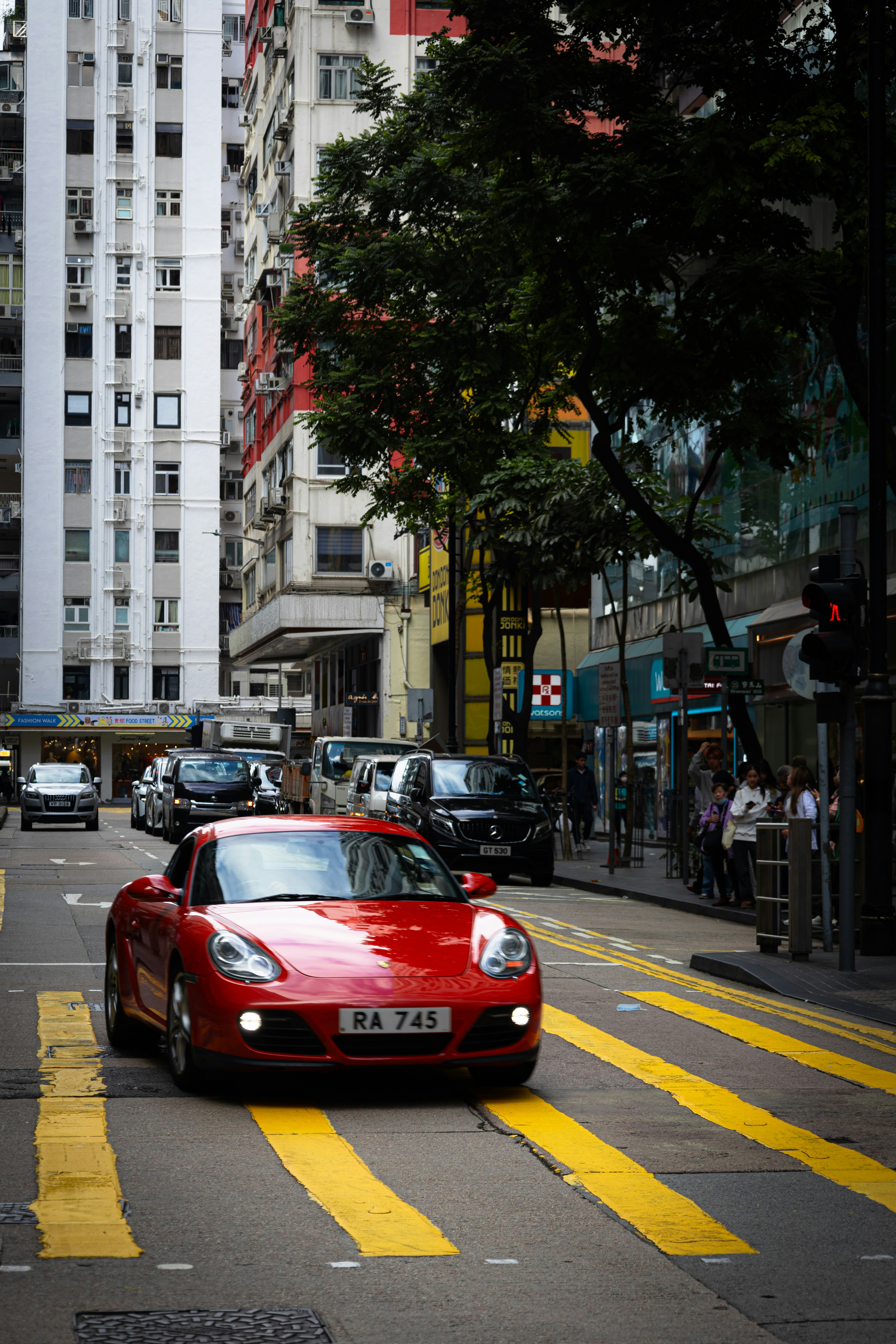 Un coche deportivo rojo circula por una concurrida calle de la ciudad.