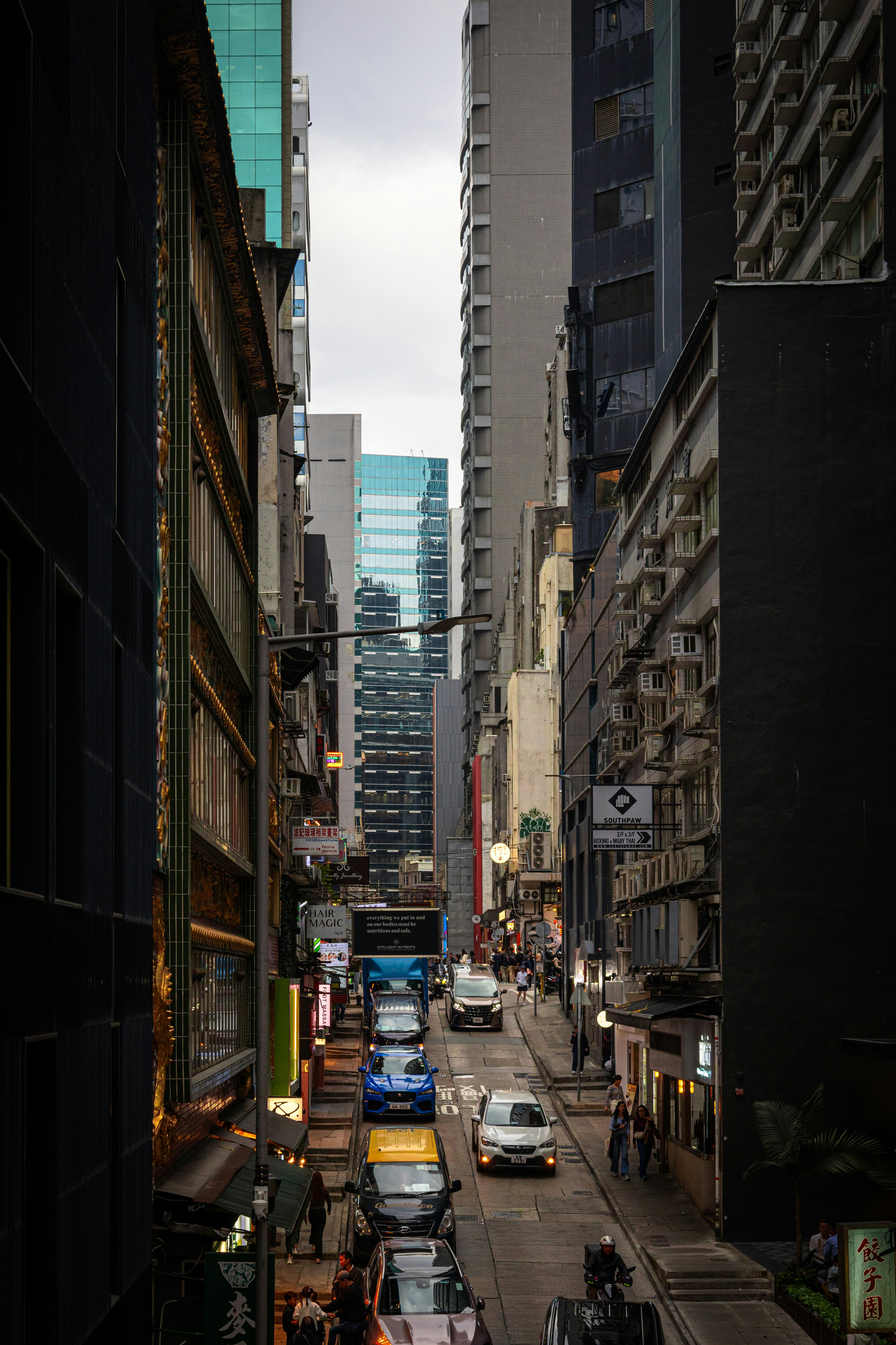 Coches circulando por una calle estrecha de la ciudad con edificios altos.