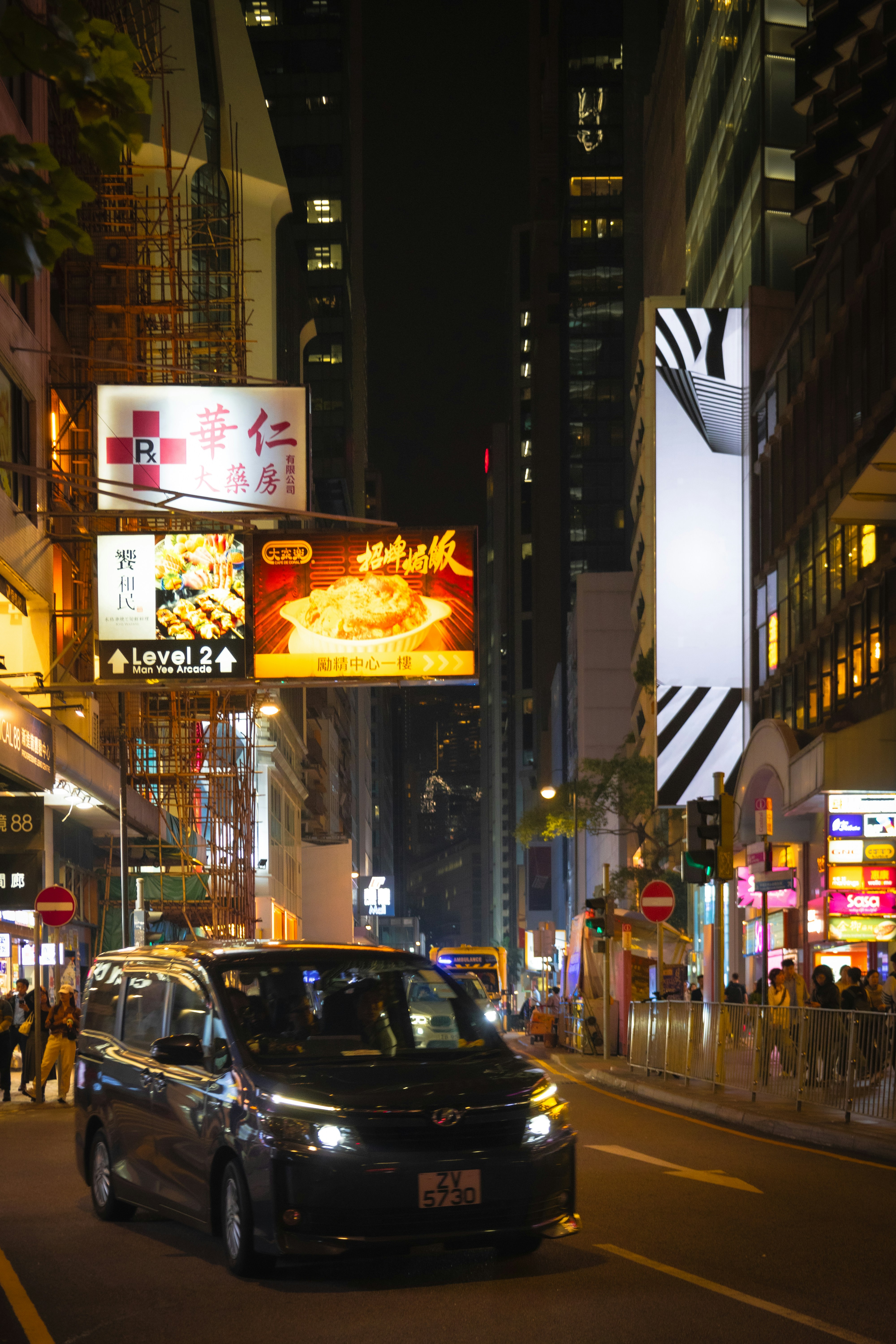 Una furgoneta circula por una calle concurrida de la ciudad por la noche.