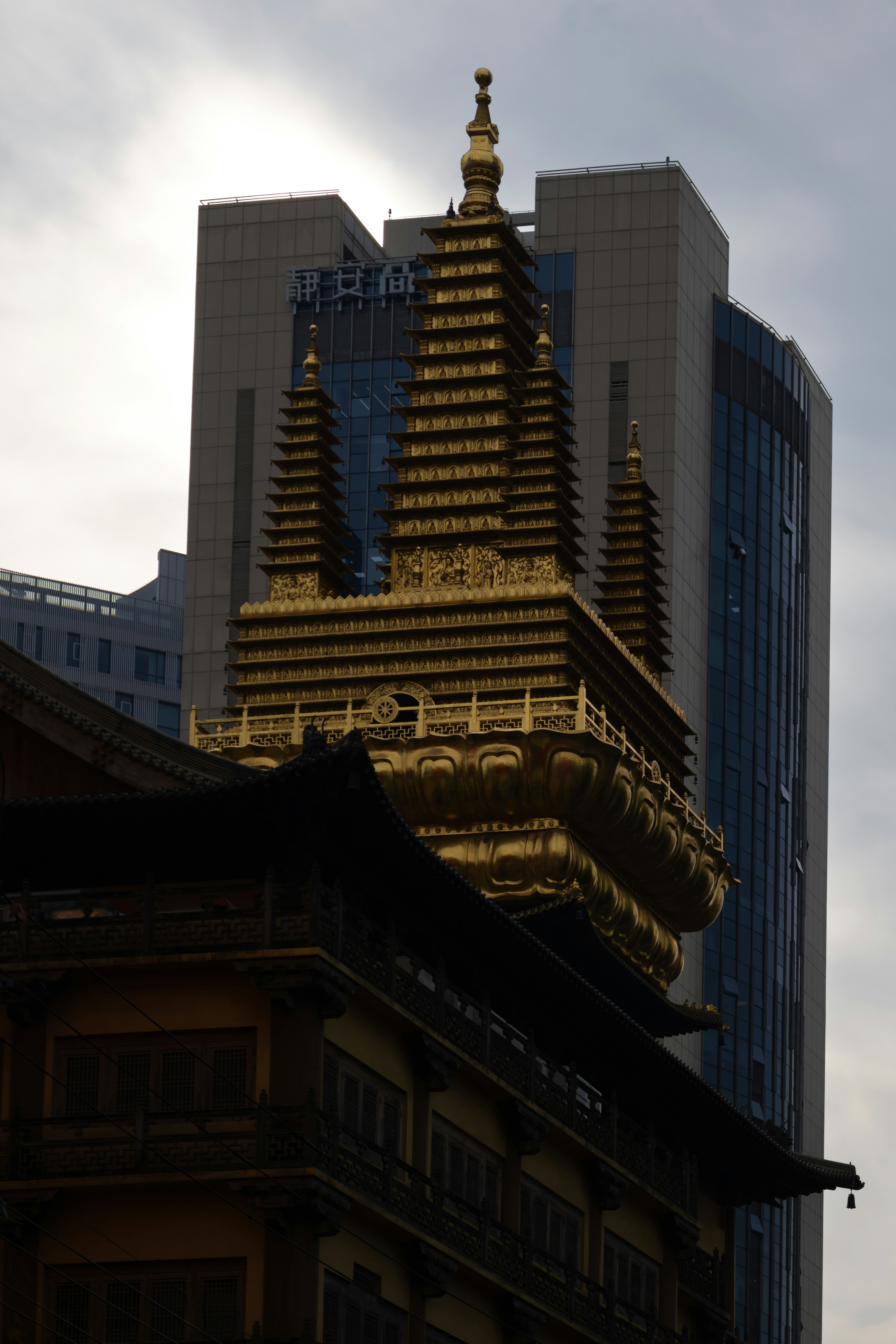 Pagoda dorada sobre un edificio tradicional junto a un rascacielos moderno.