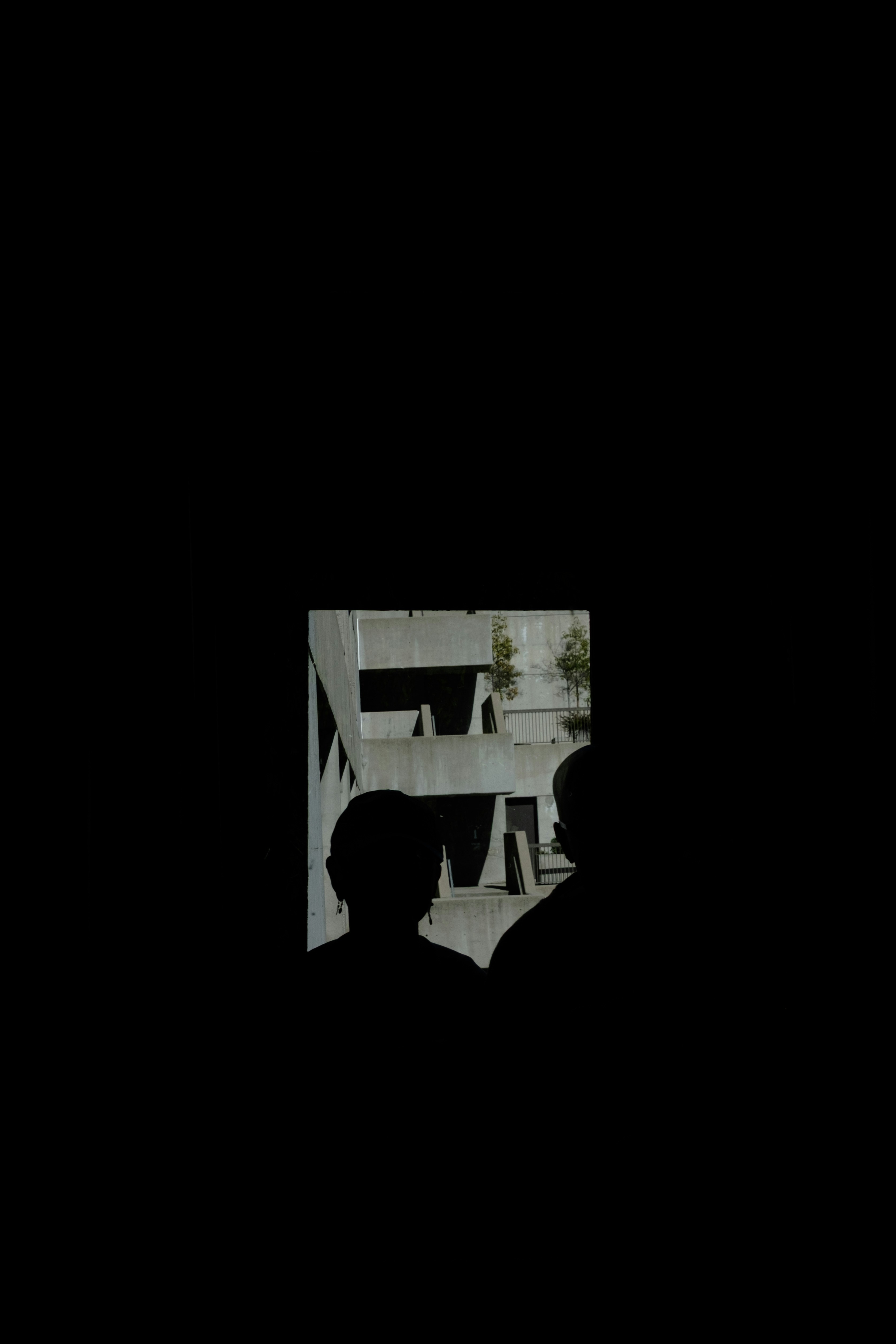 Silhouettes of two people against concrete architecture.