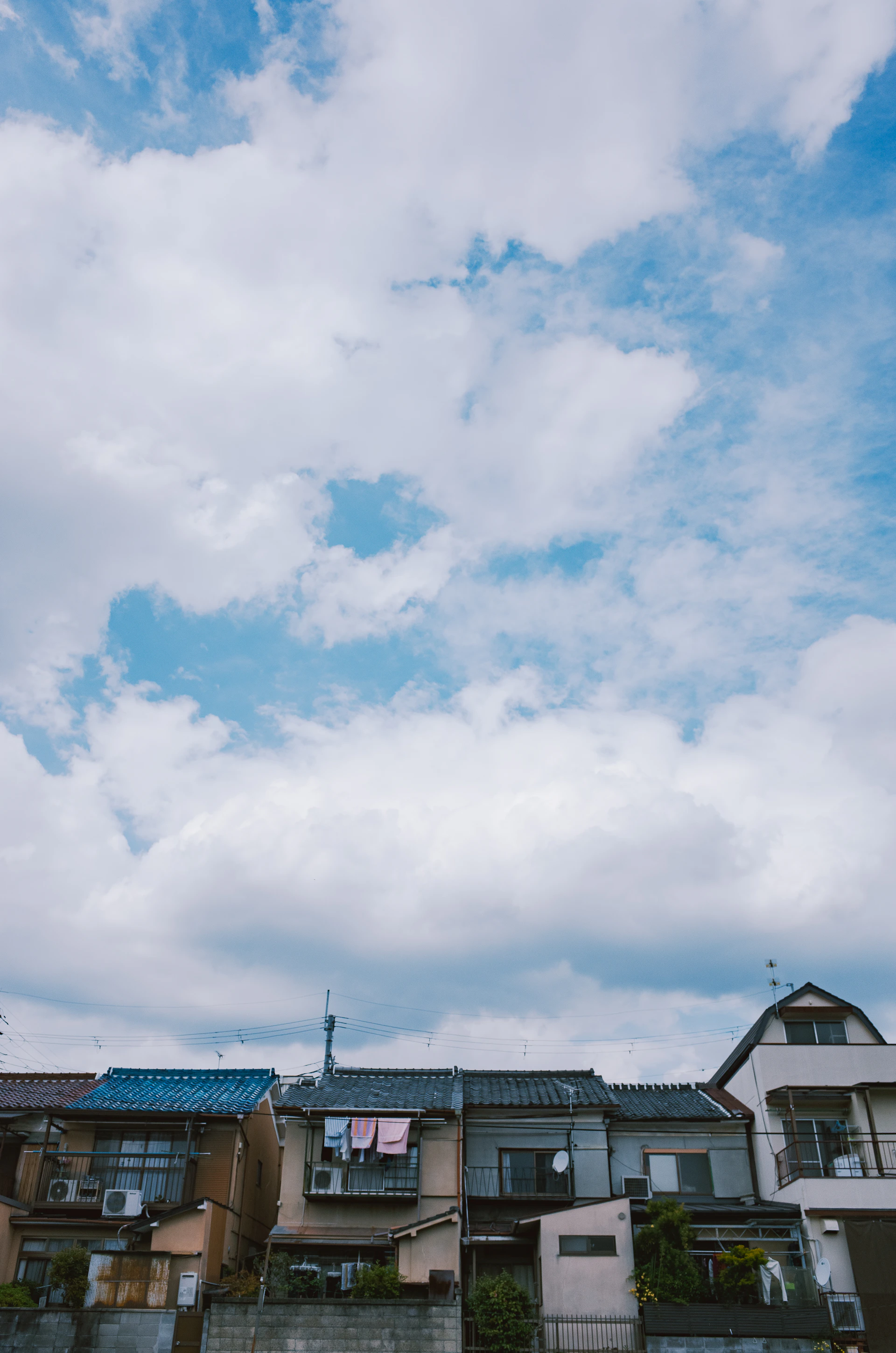 Row of houses under a cloudy blue sky.