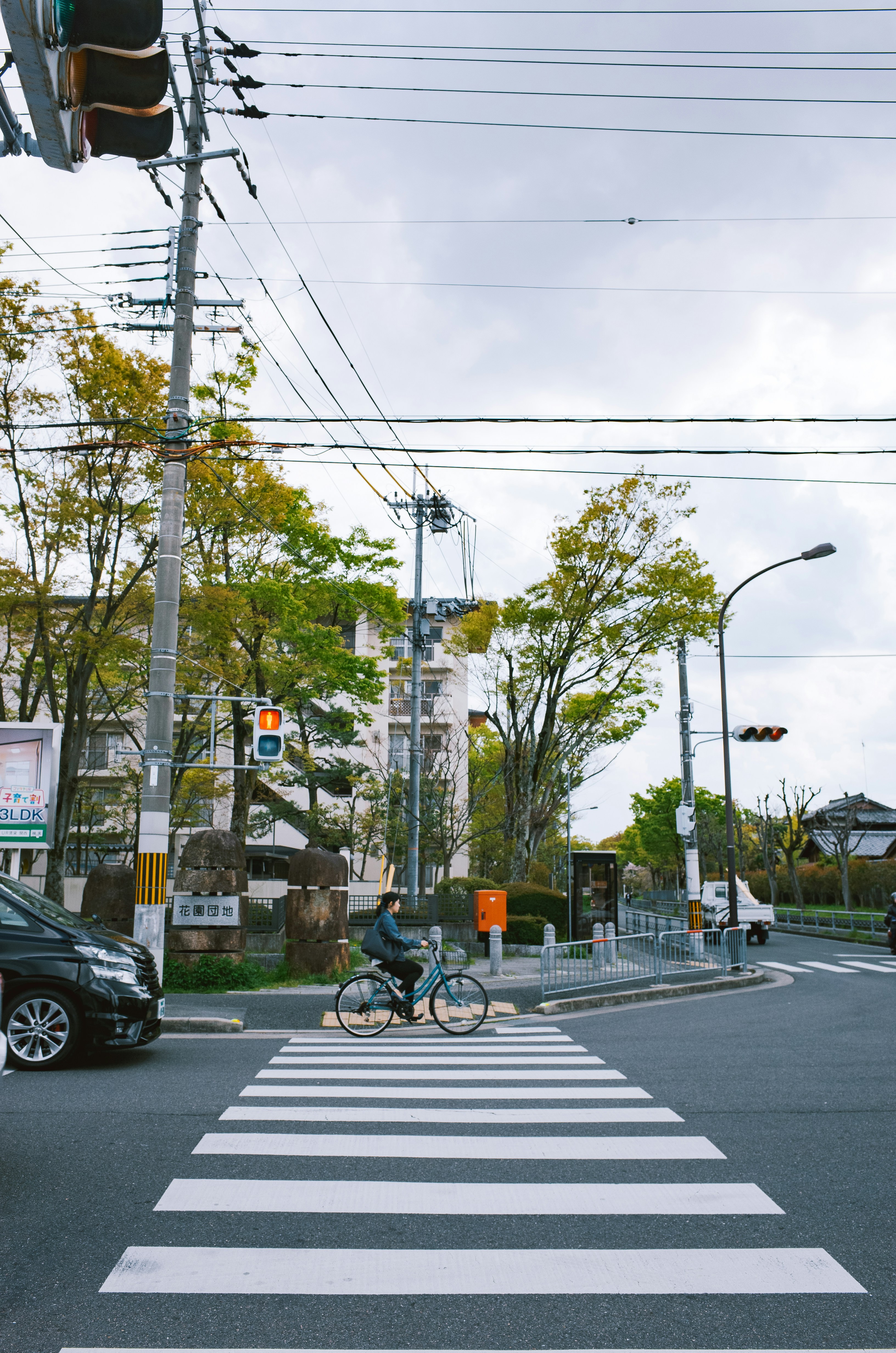 Cyclist rides across a crosswalk on a cloudy day.