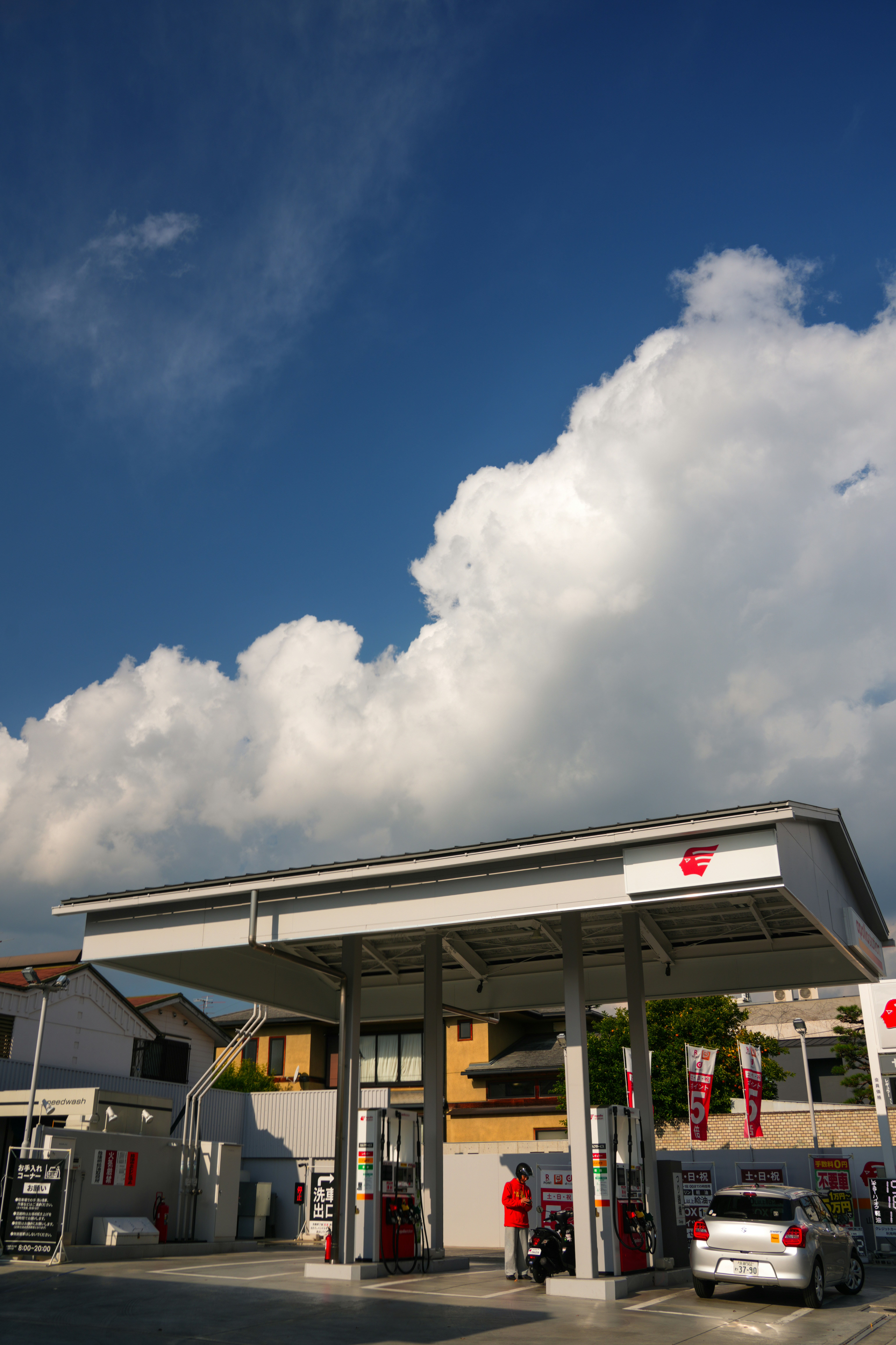 Pom bensin dengan mobil di bawah langit biru mendung
