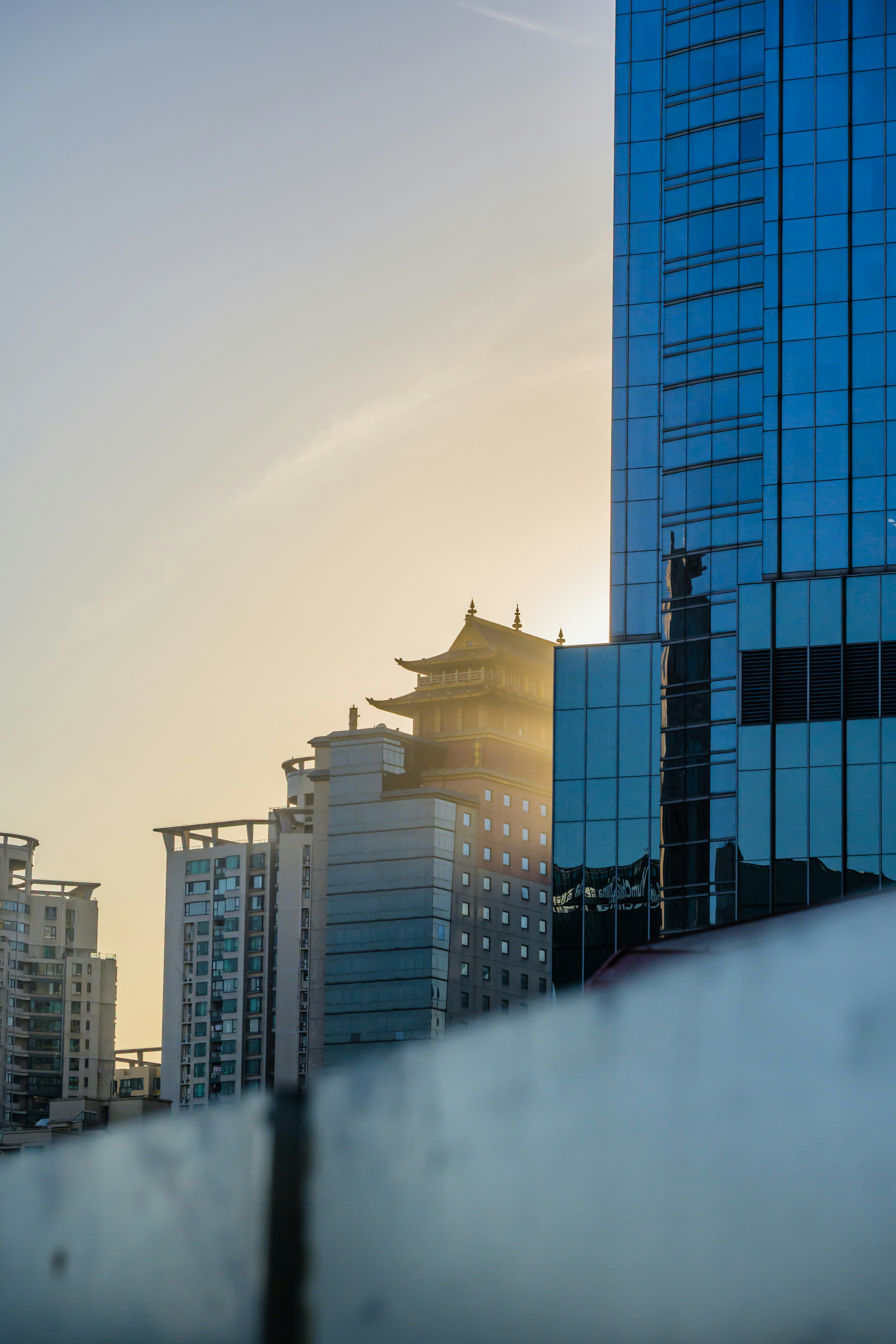 Edificios modernos con pagoda tradicional al atardecer.