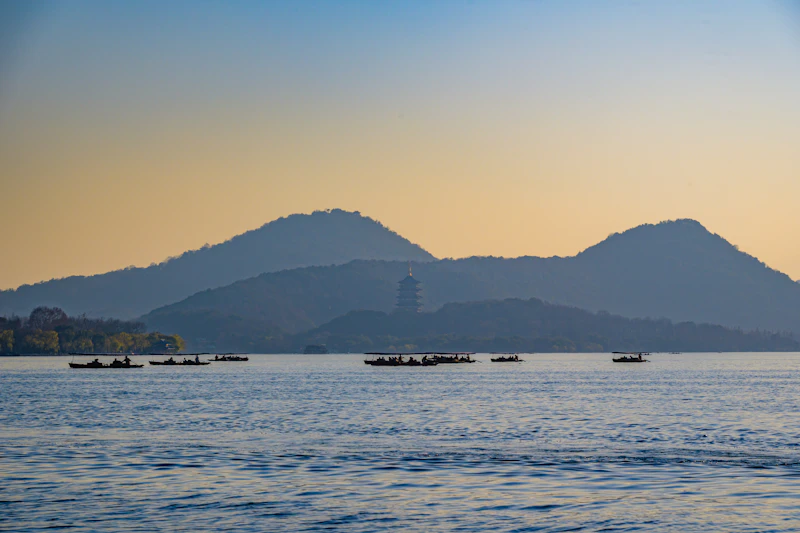 Boats on a scenic lake at sunset surrounded by mountains