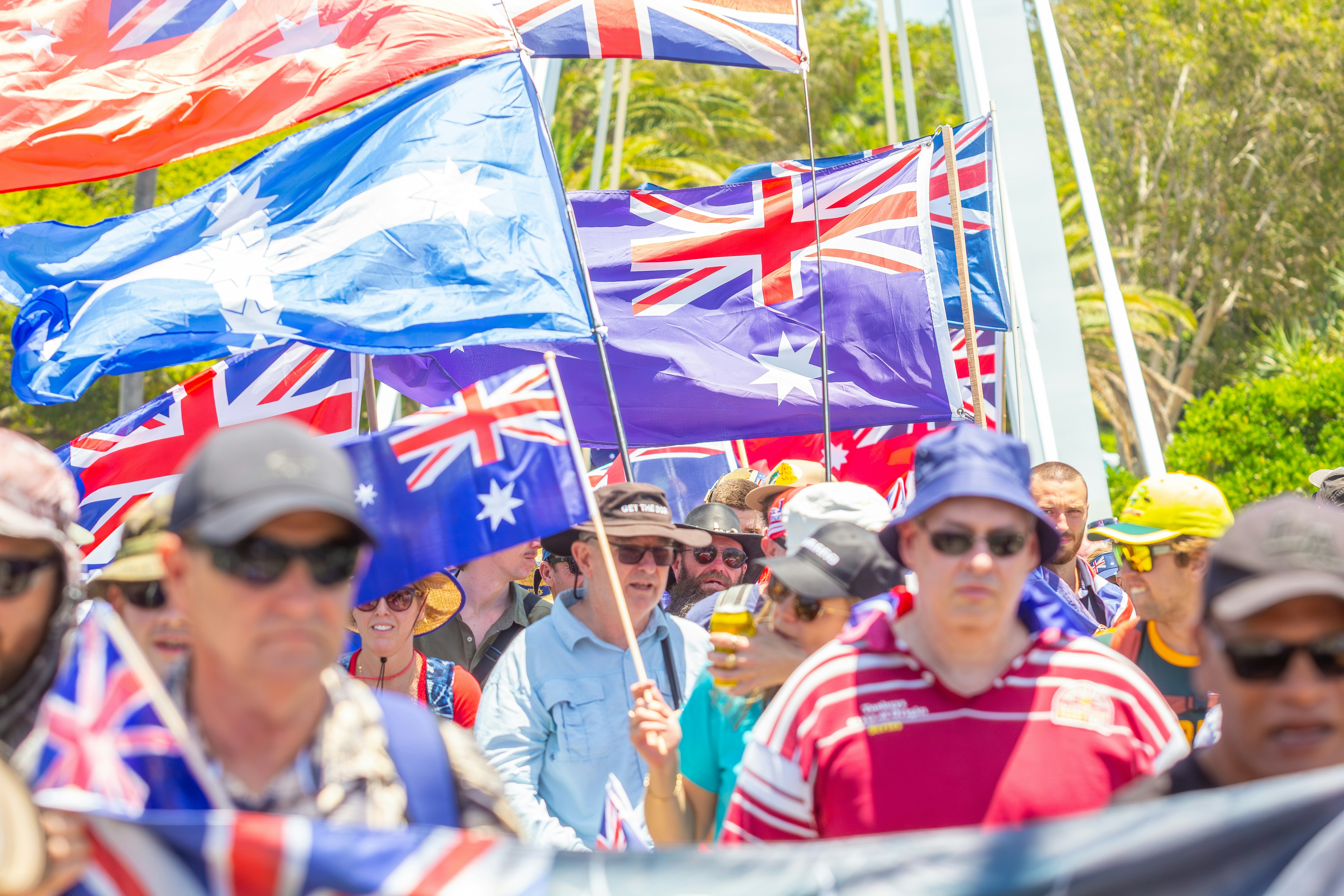 Um grupo de pessoas segurando bandeiras australianas em um comício.