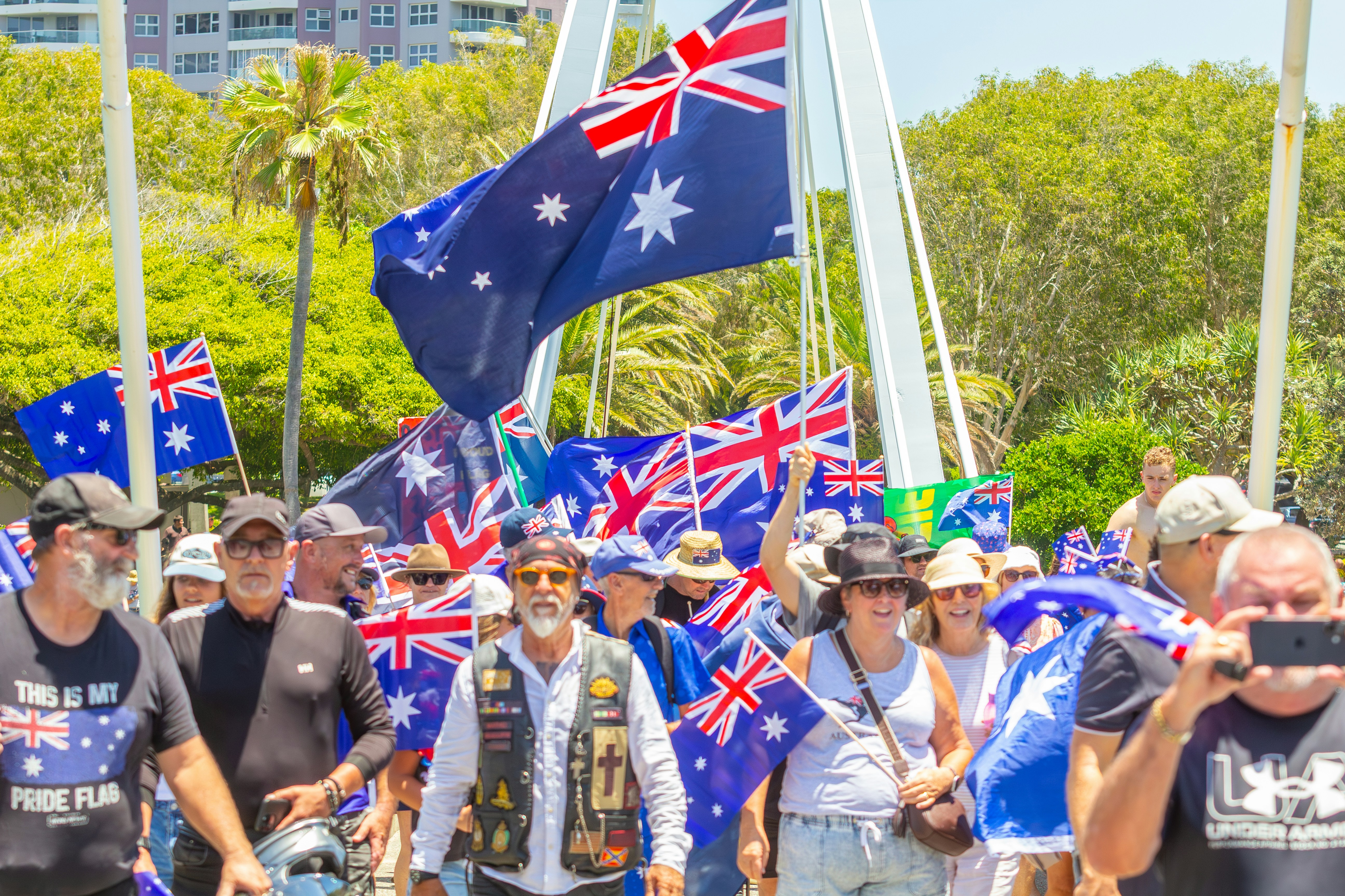 Crowd of people waving australian flags outdoors