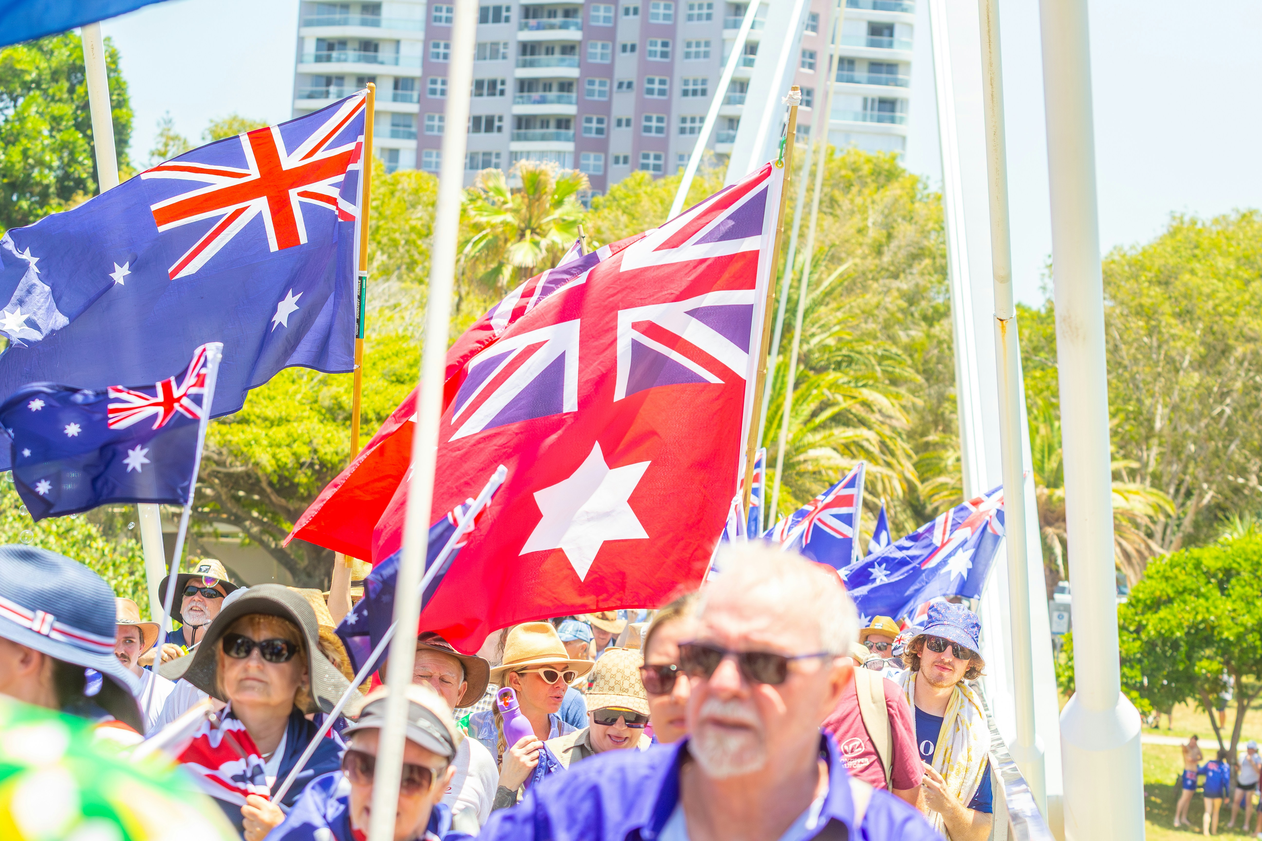 People waving australian flags at an outdoor event.