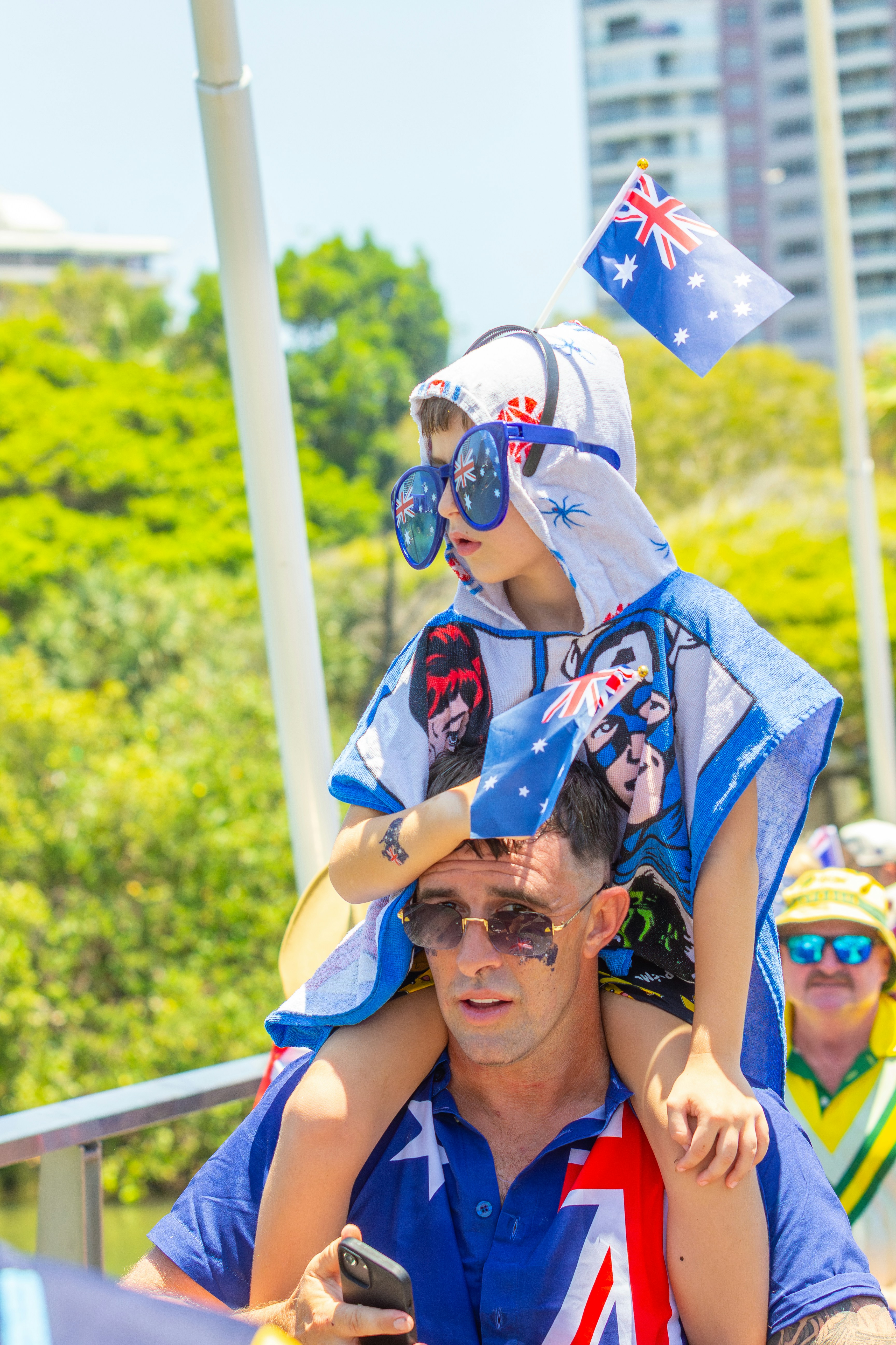 Father carries child wearing australian flag attire.