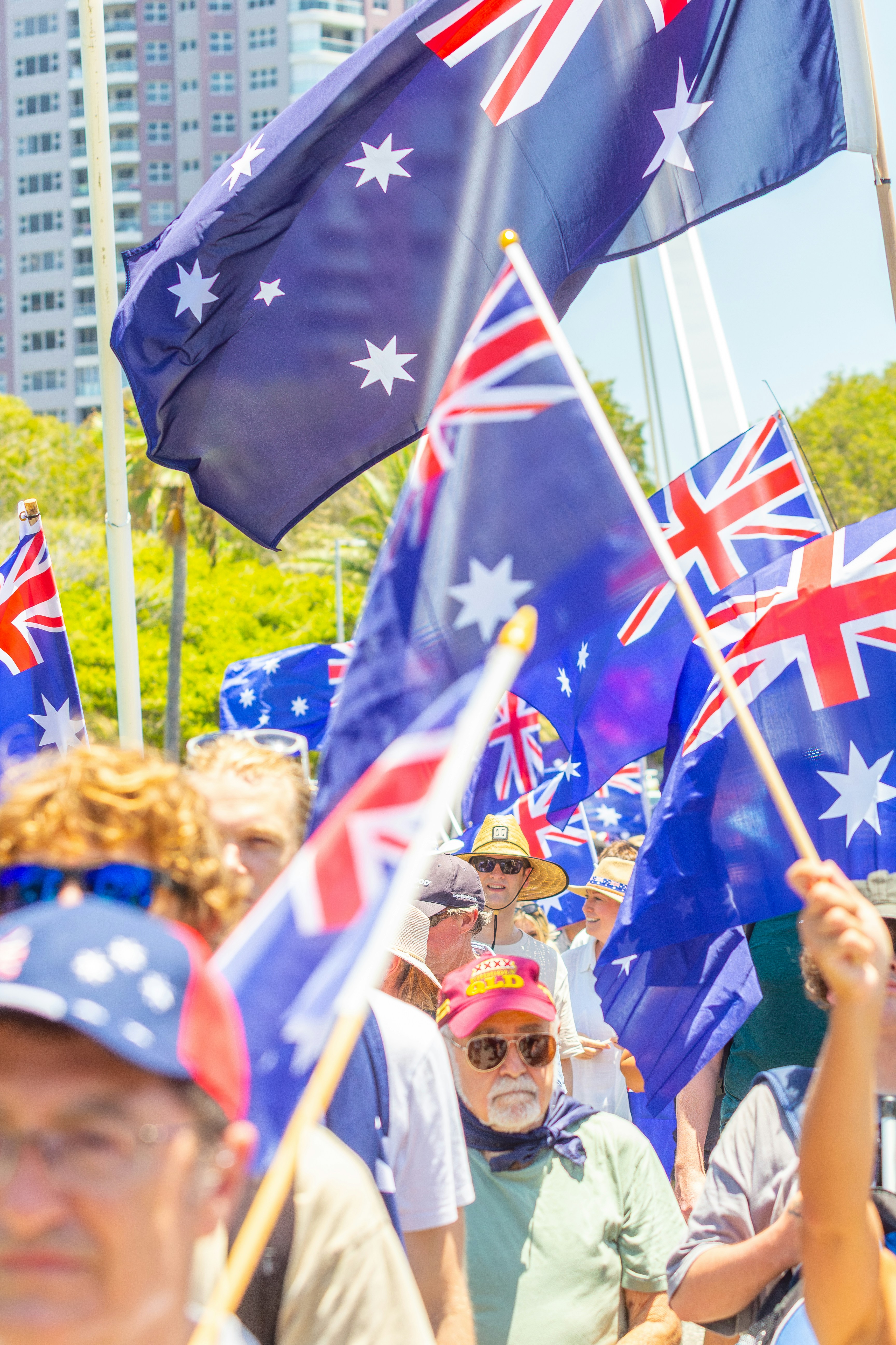 Crowd waving australian flags under a bright sky