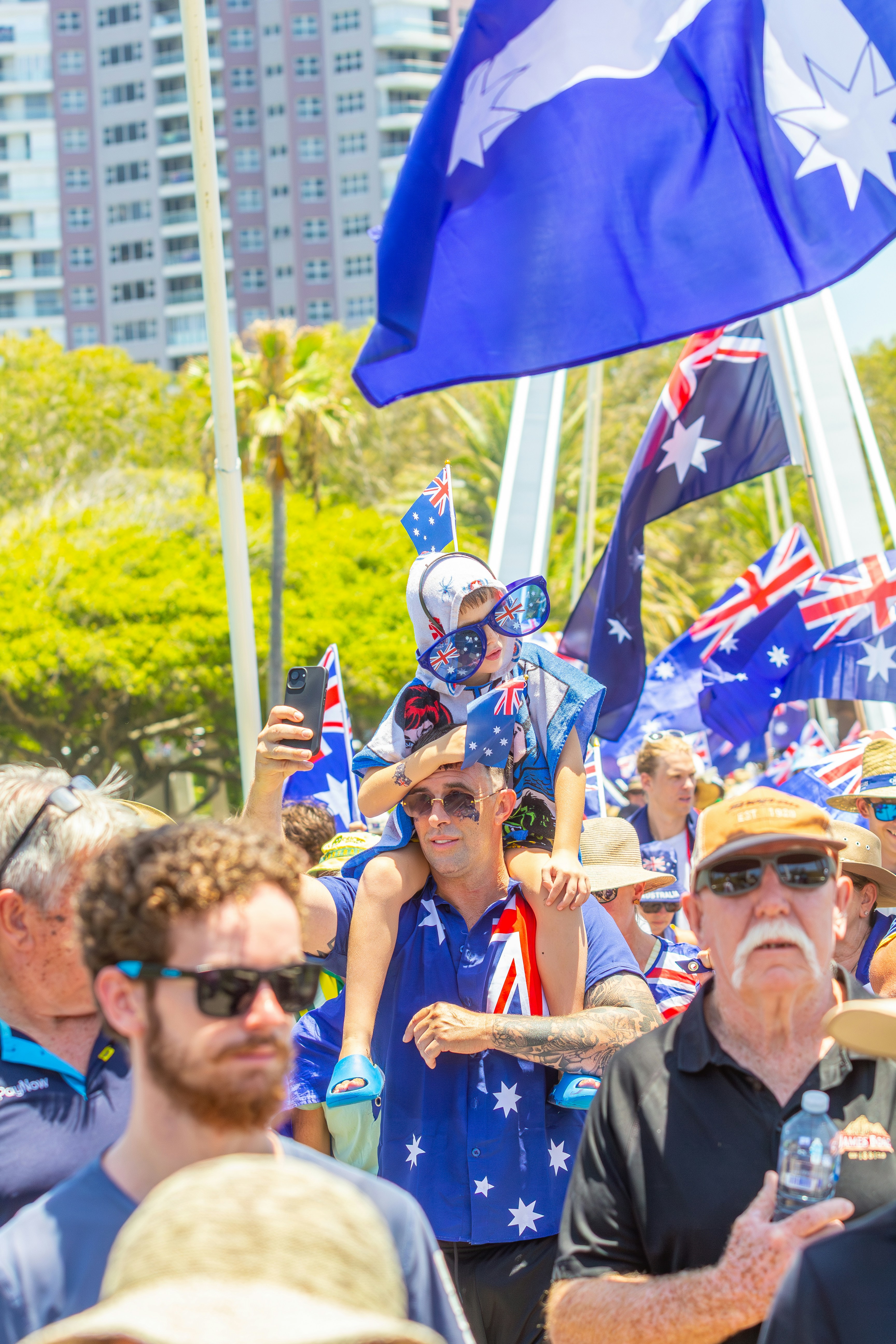 People waving australian flags at an outdoor event.