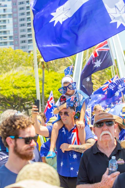 People waving australian flags at an outdoor event.