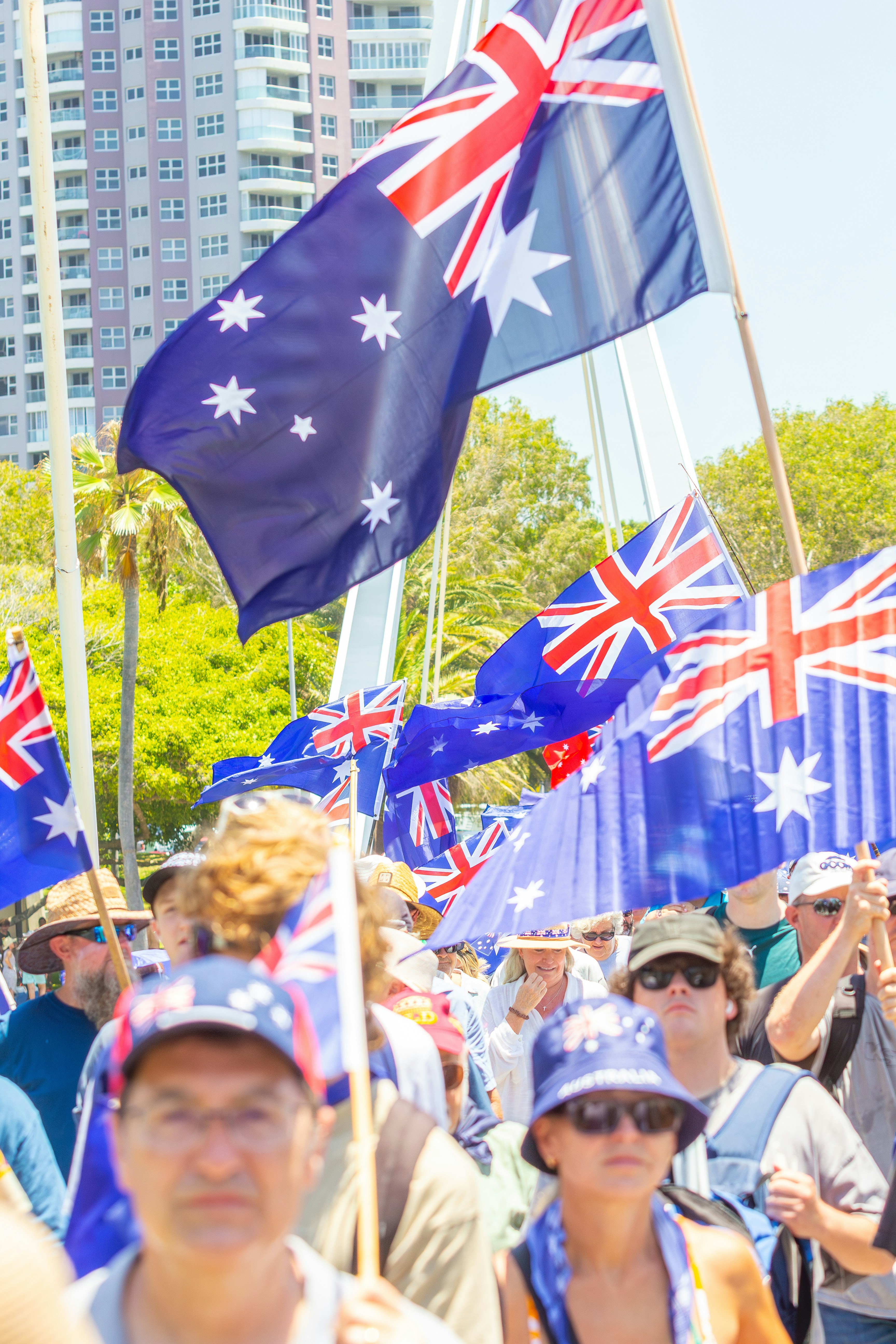 People waving australian flags at a sunny outdoor event