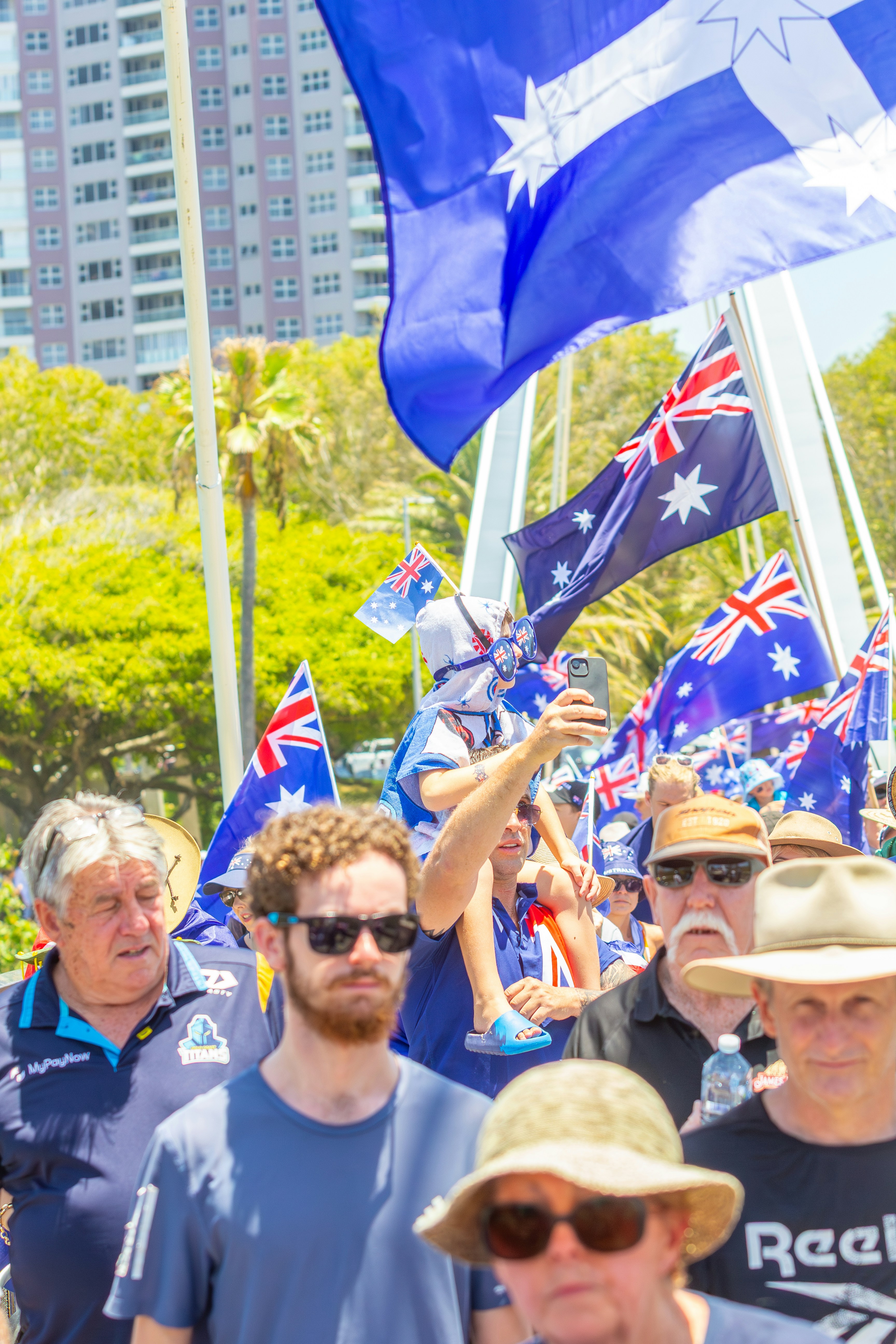 Multitud de personas ondeando banderas australianas en un evento al aire libre