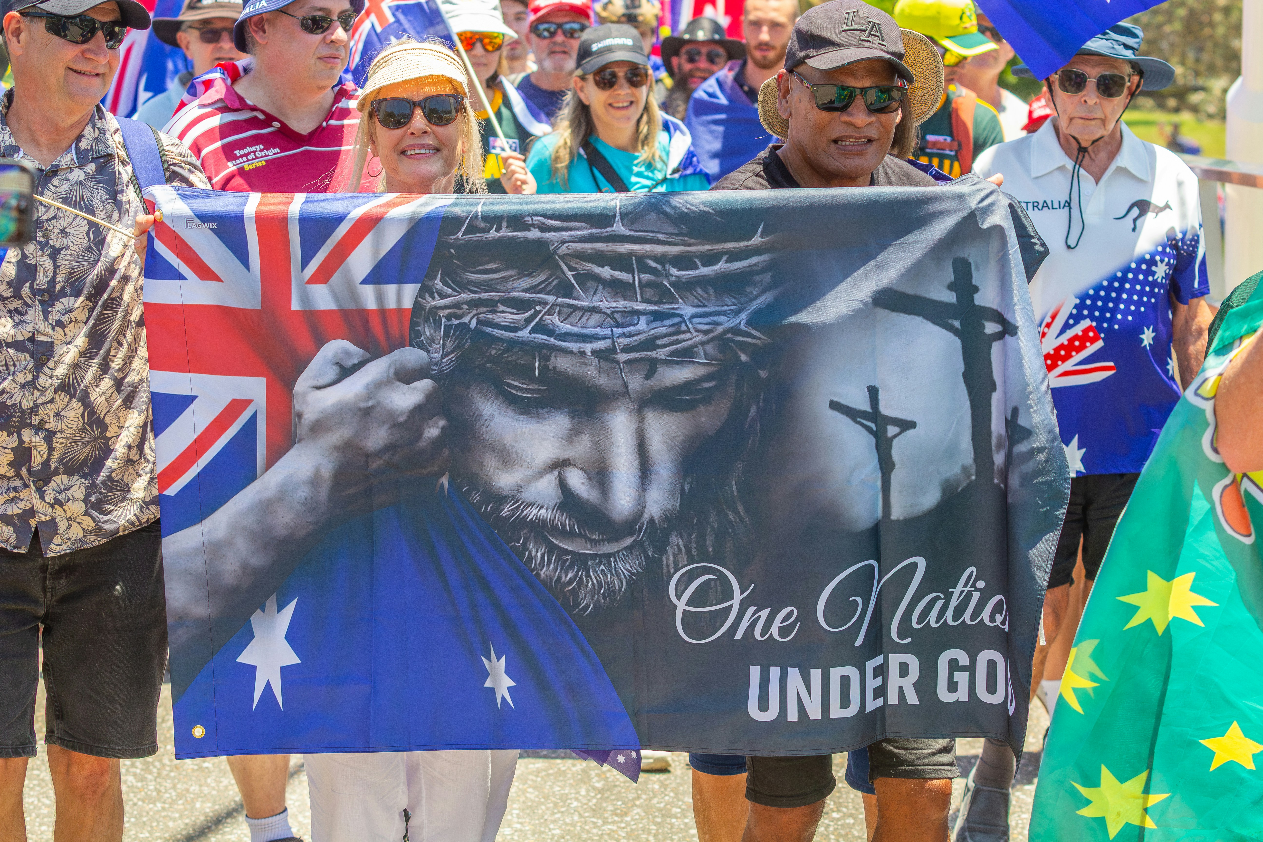 People march with a banner featuring jesus and australian flag.