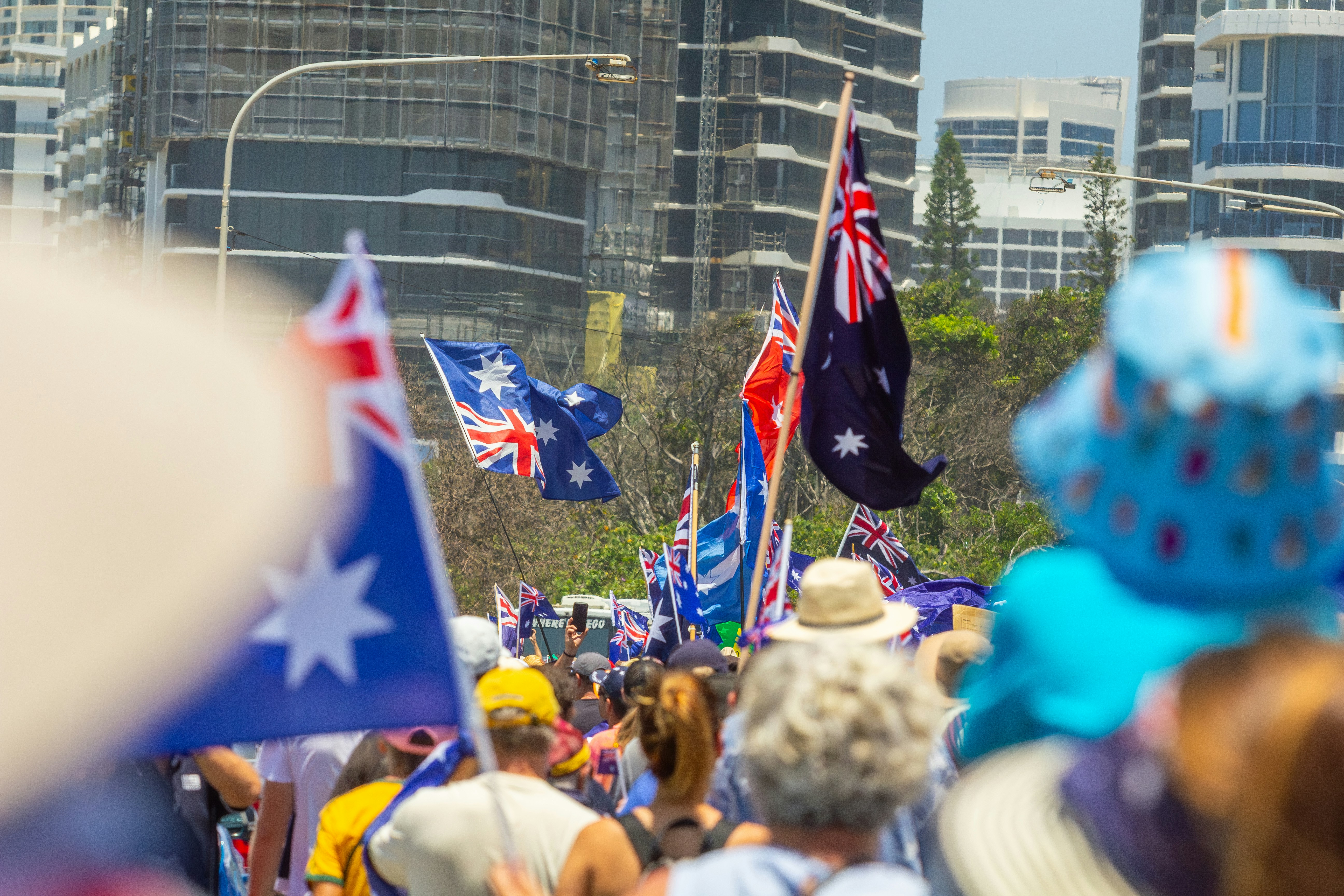 Crowd of people waving australian flags at an outdoor event