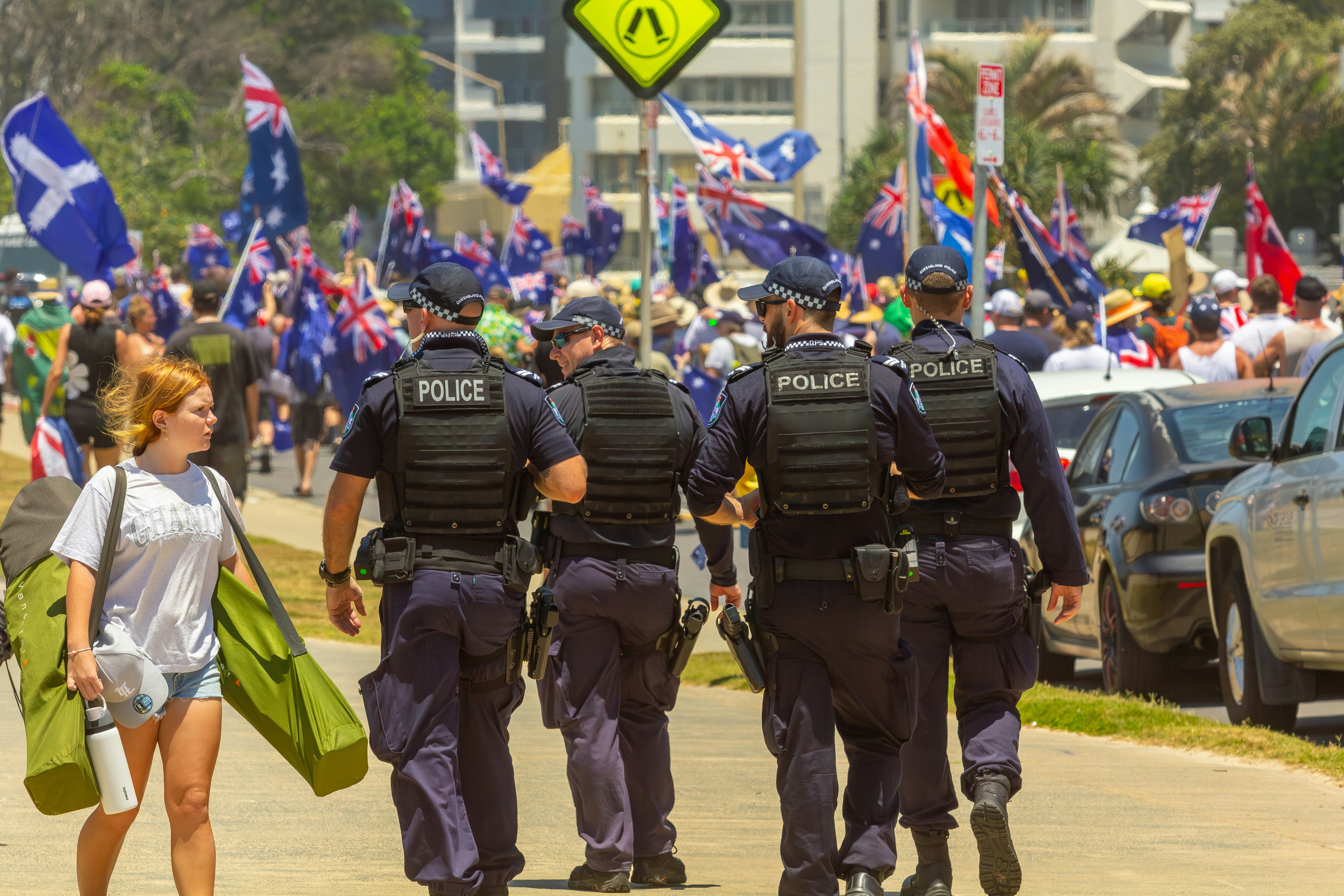 Police officers walk past a crowd with flags