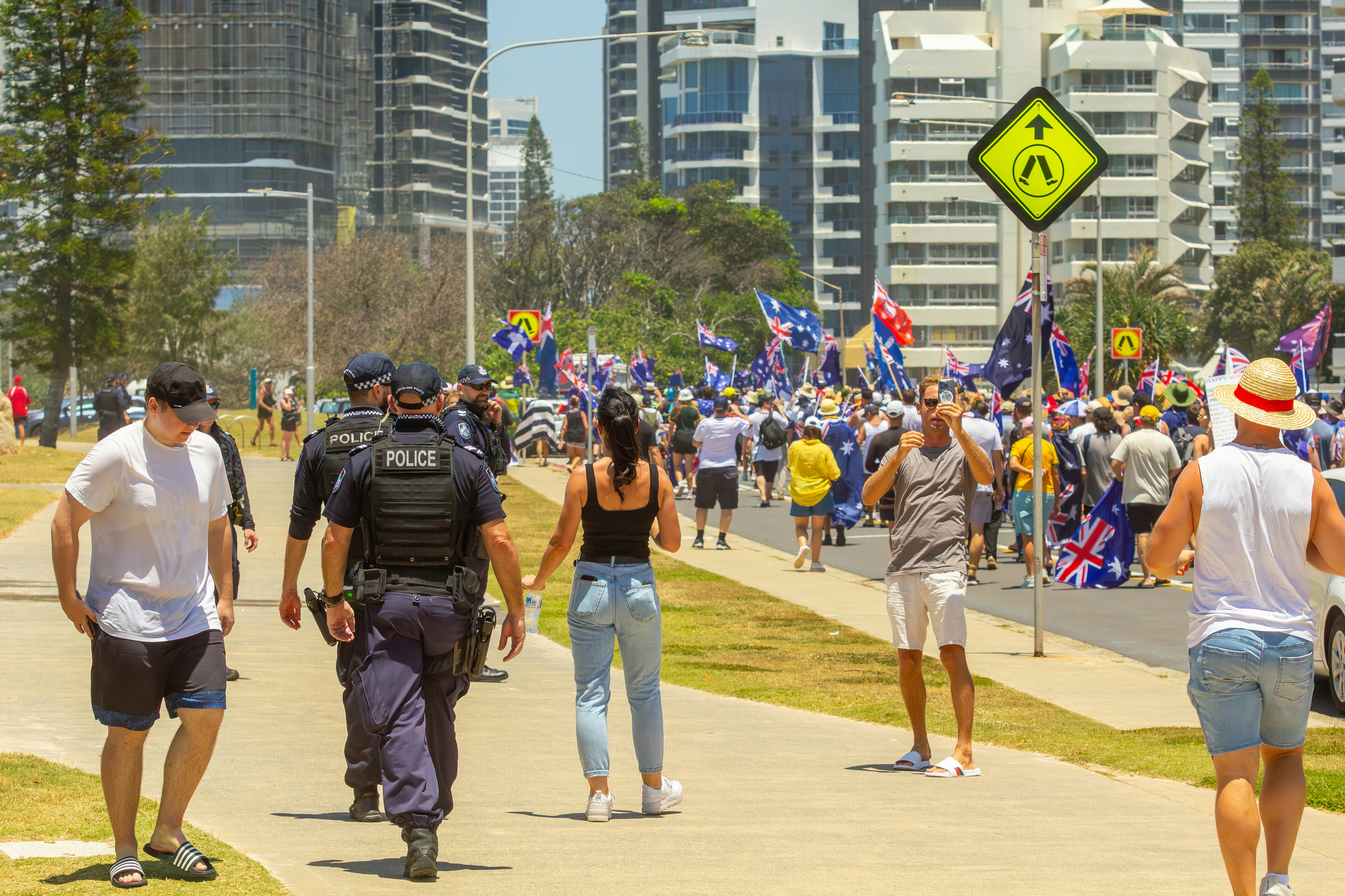 Police officers walk past a crowd with flags. photo – Free Crowd Image ...