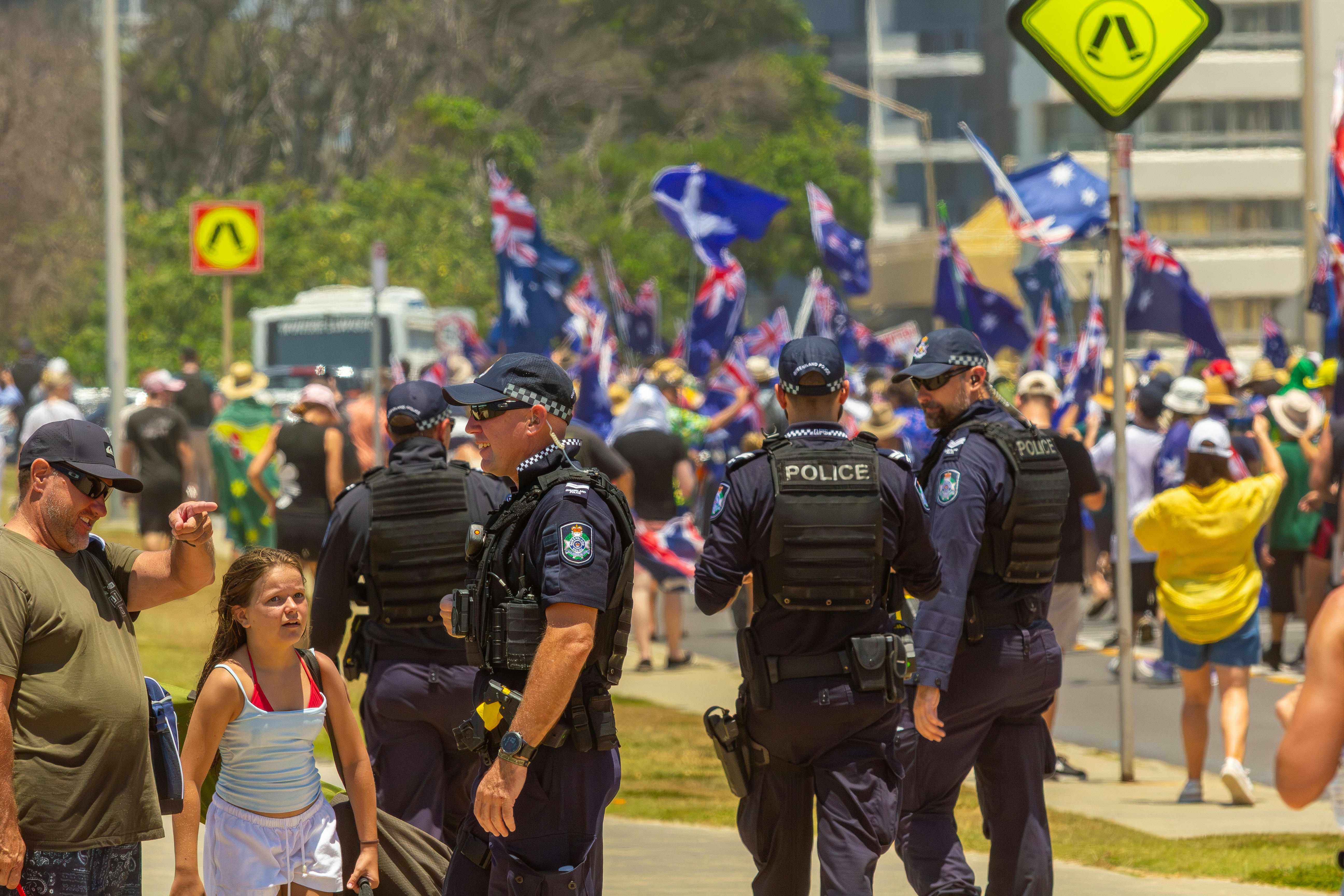 Police officers observe a crowd with australian flags.