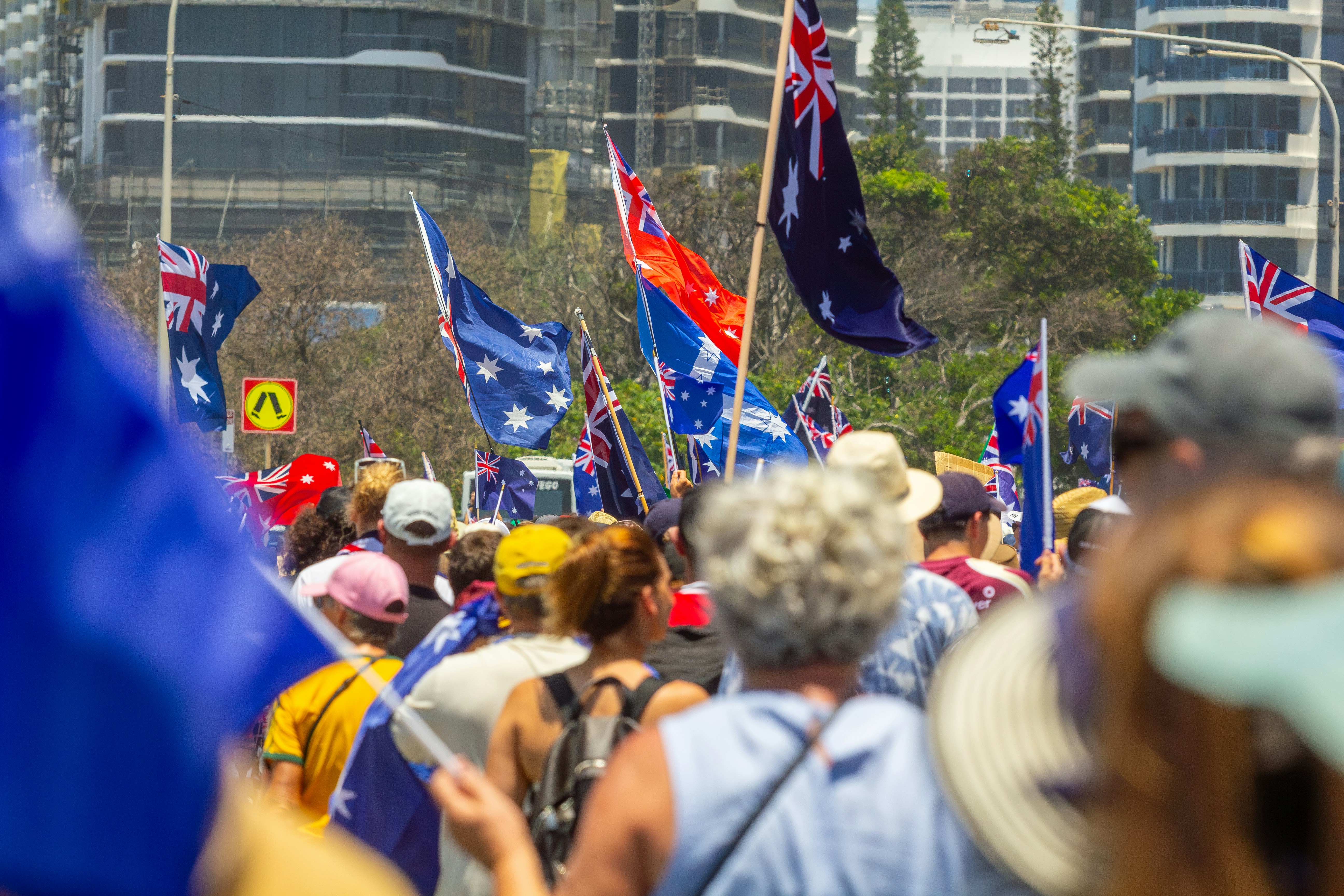 Crowd waving australian flags at a rally.