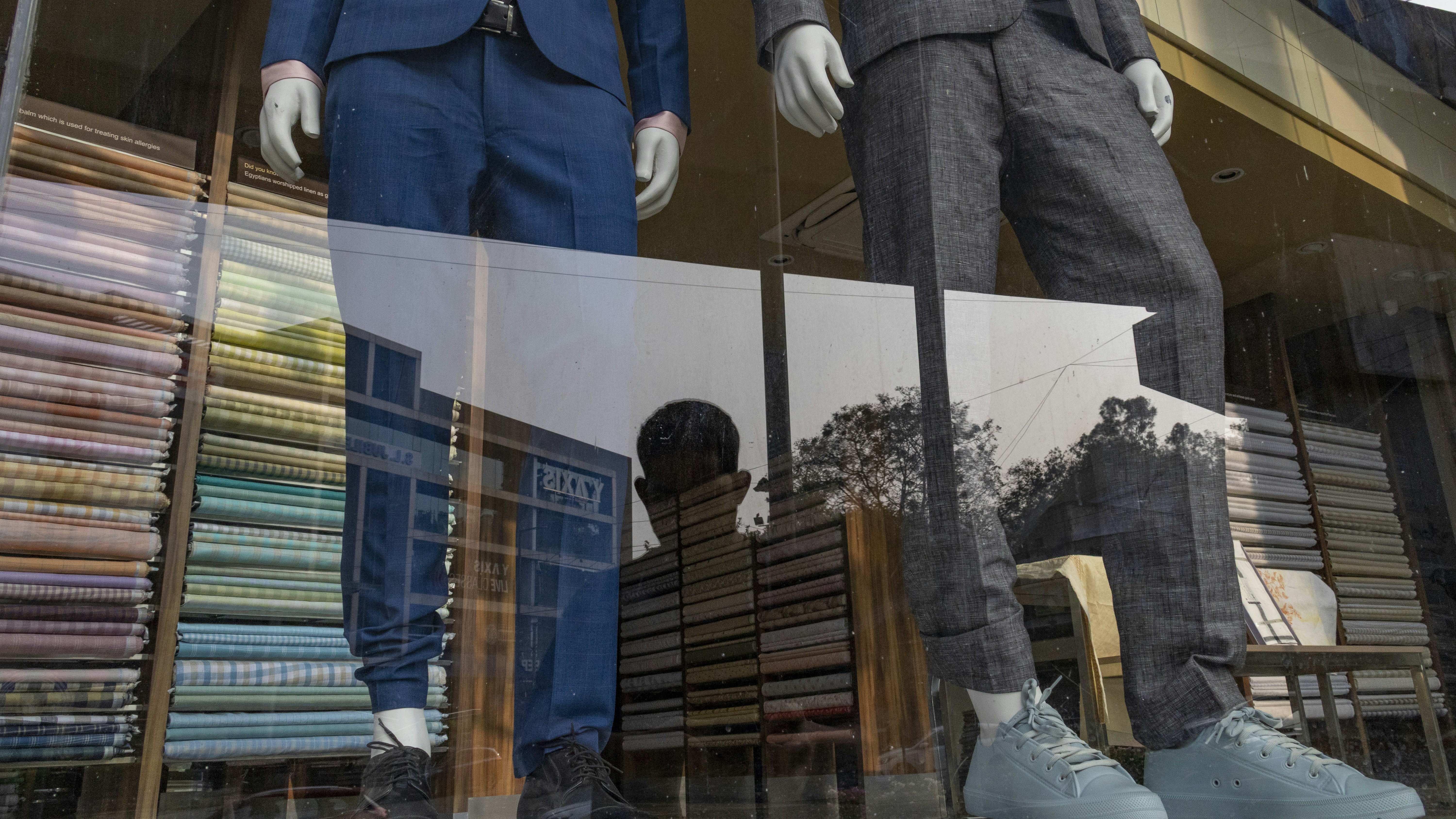 Mannequins in suits displayed in a shop window.