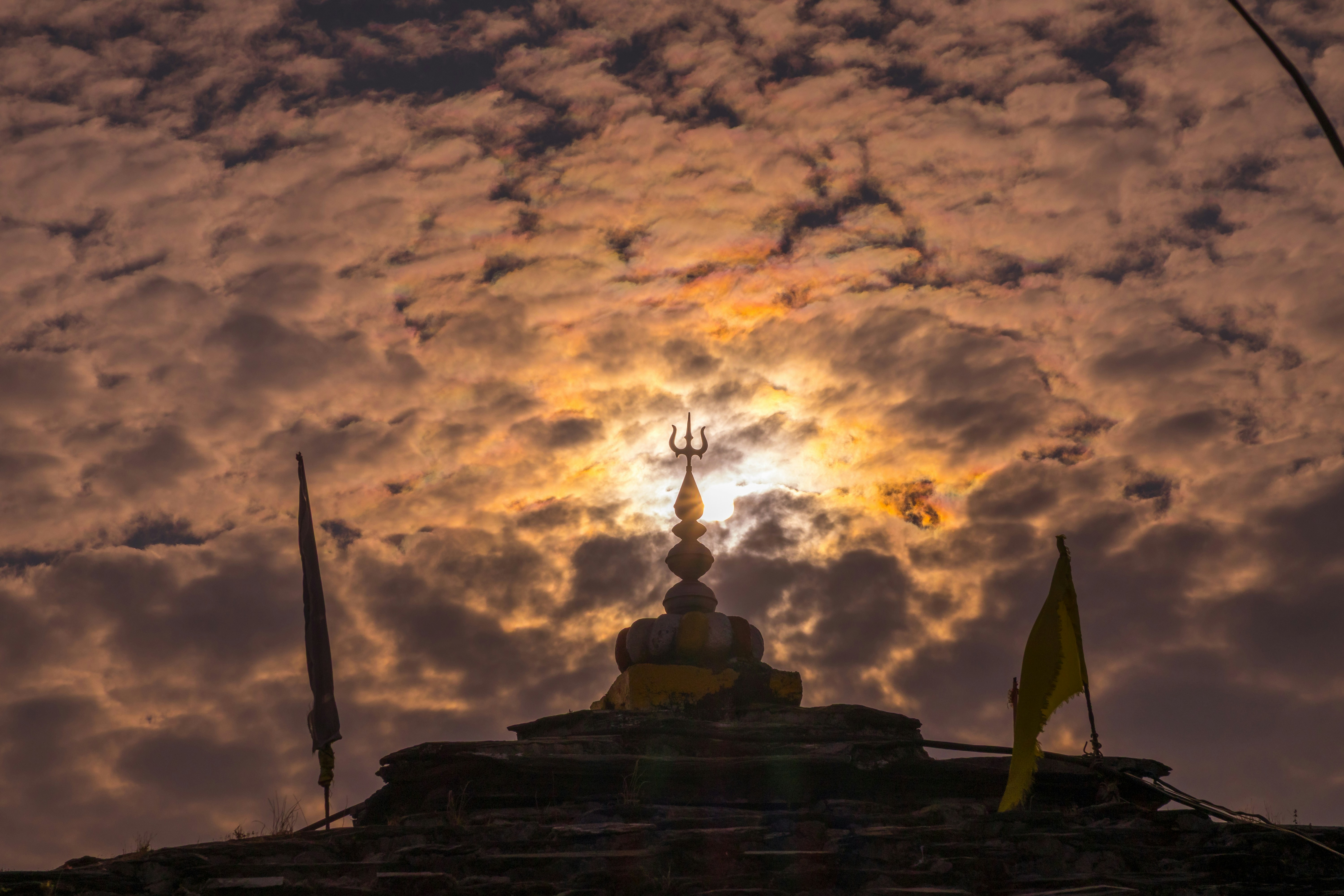 Sunlight shines through dramatic clouds over temple roof.