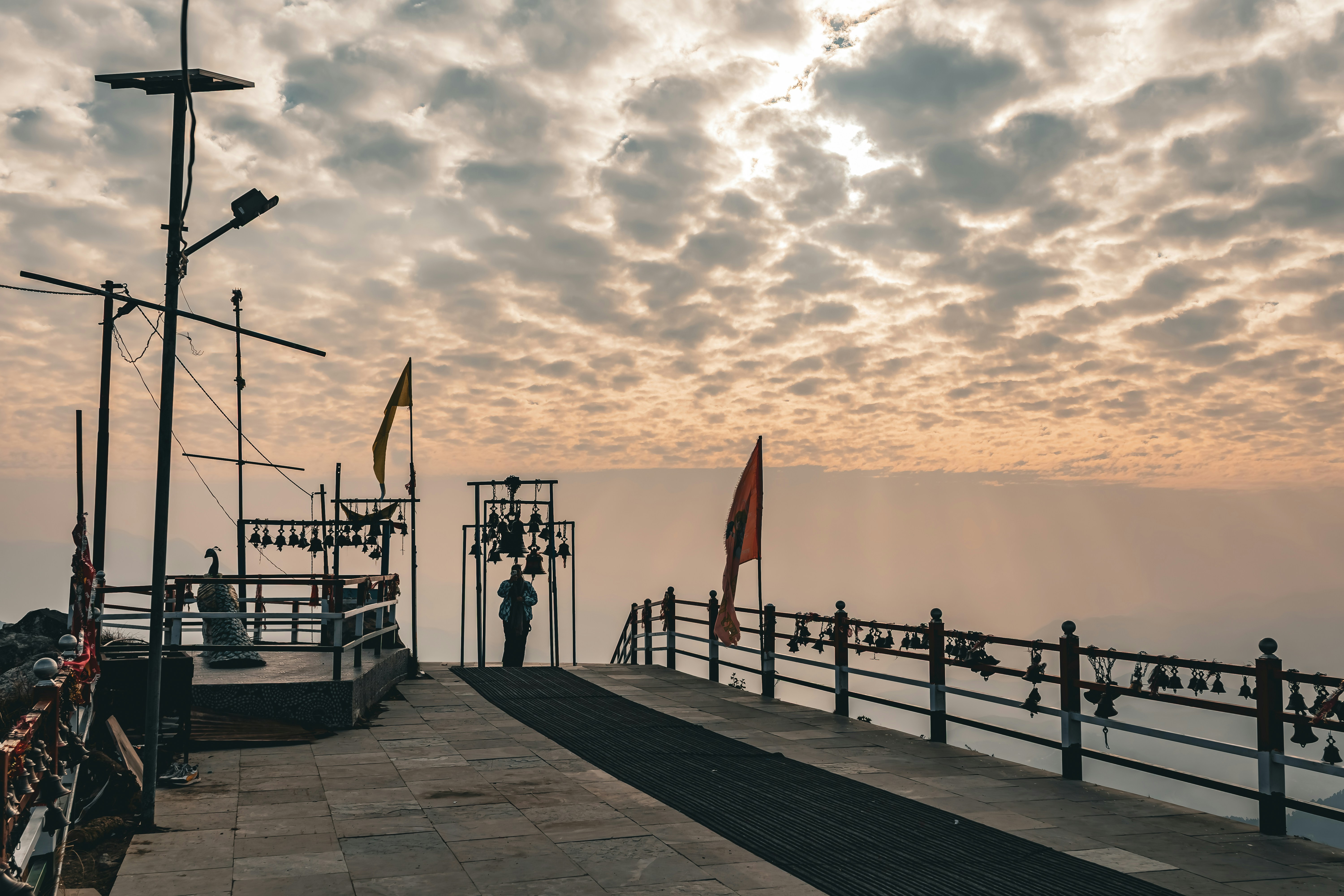 A pathway leading to a temple with bells and flags