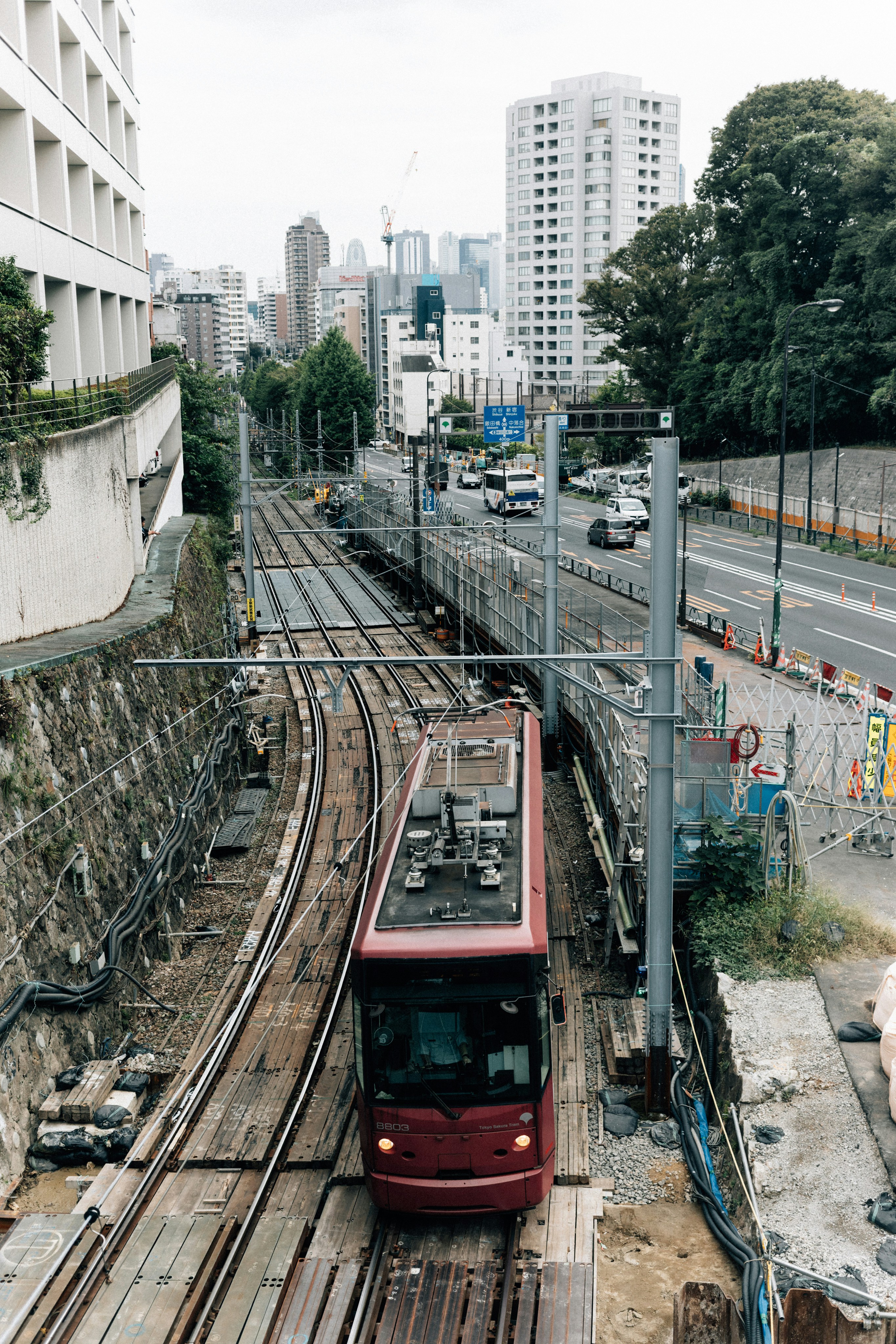 A red tram travels on tracks through a city.