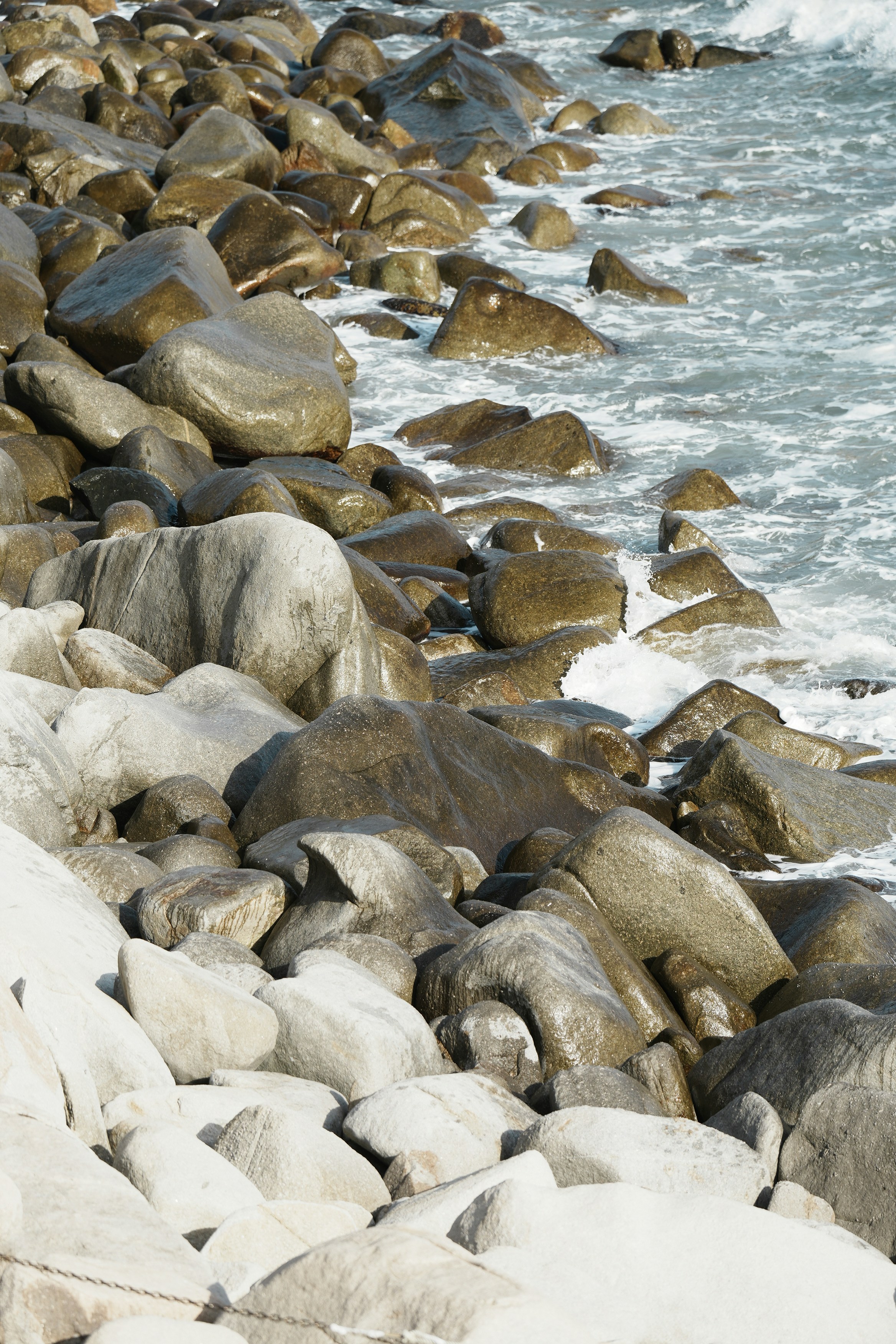 Rocas mojadas en una orilla rocosa con olas suaves