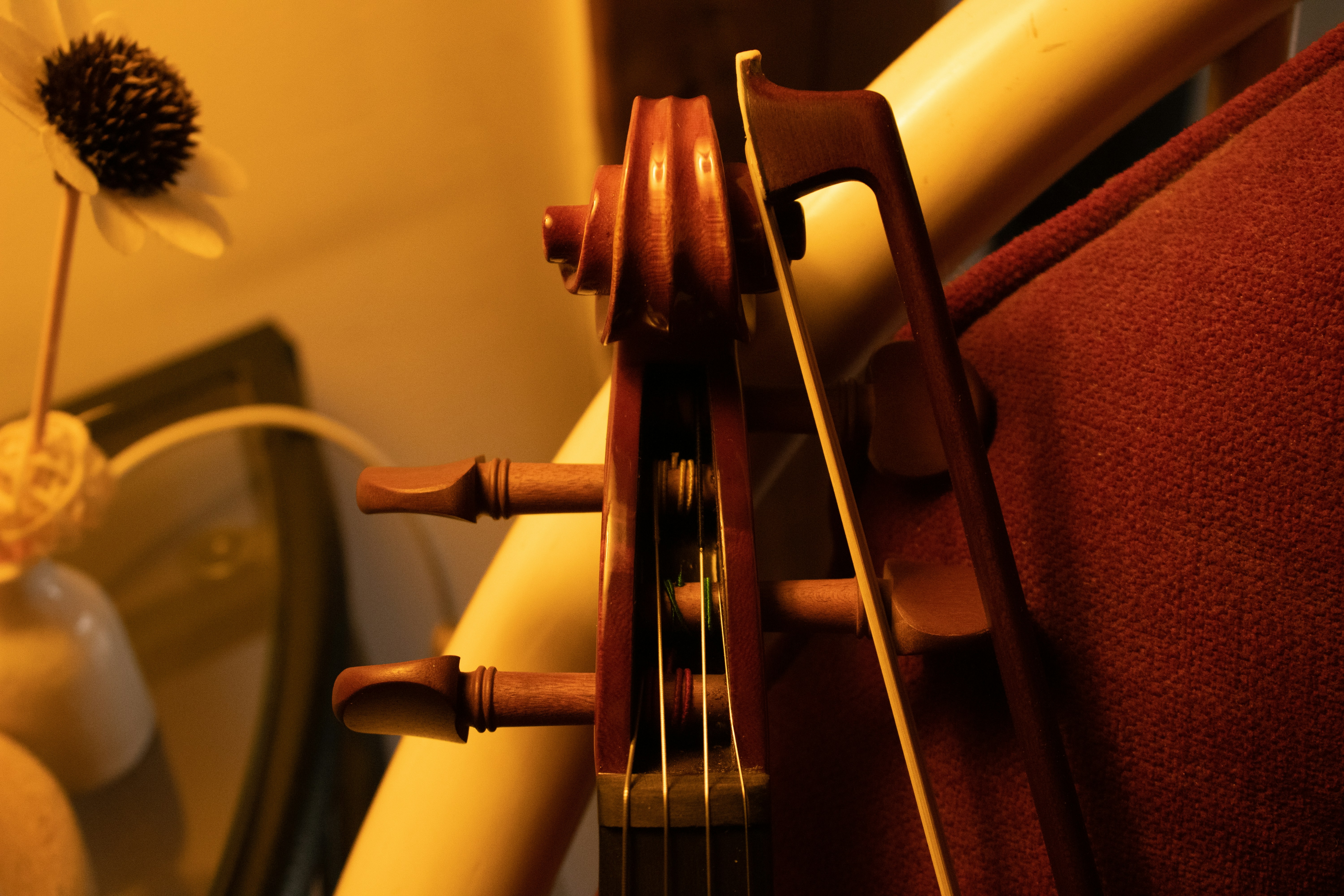 Close-up of a violin scroll and bow on a chair