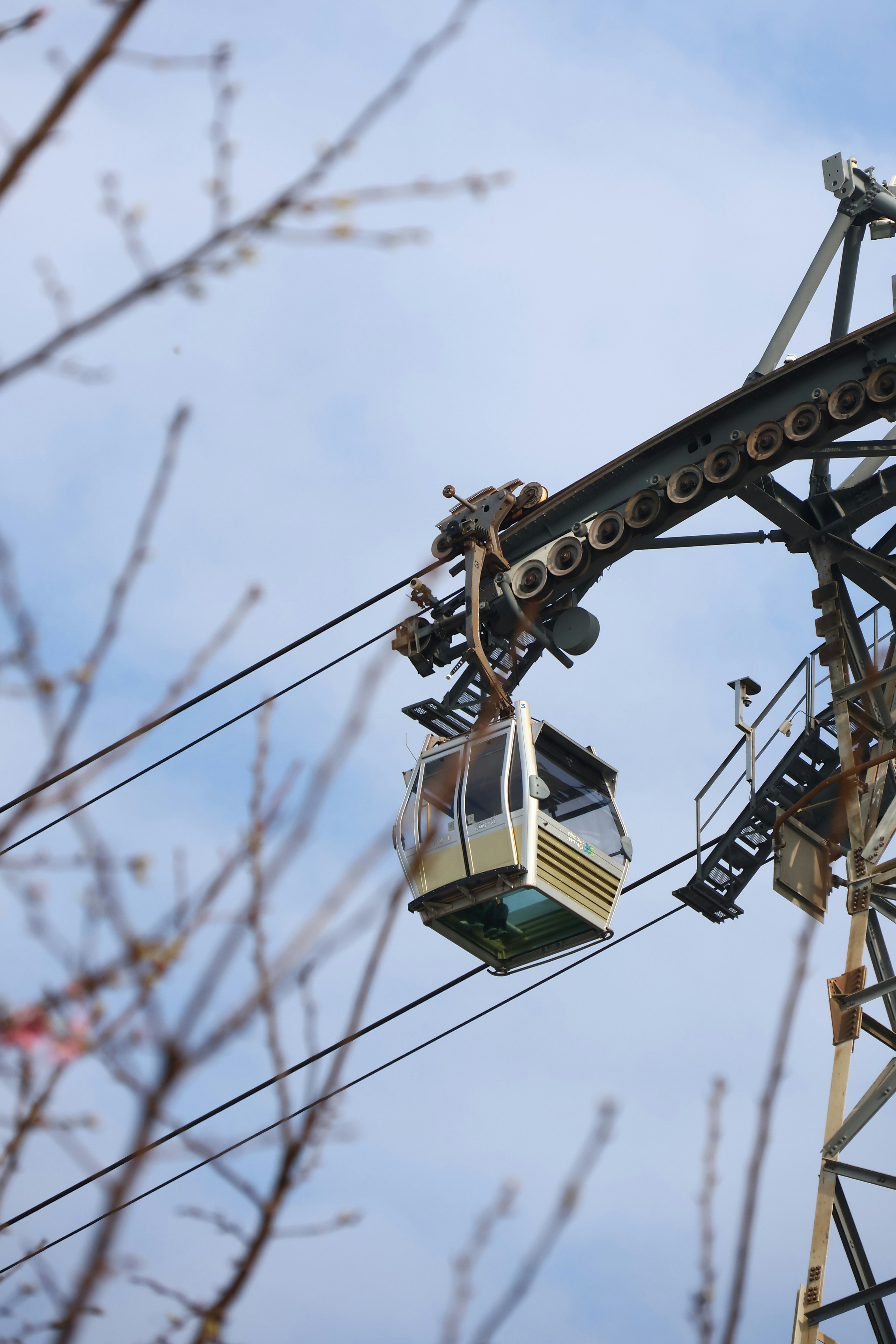 A cable car travels on a wire against the sky.