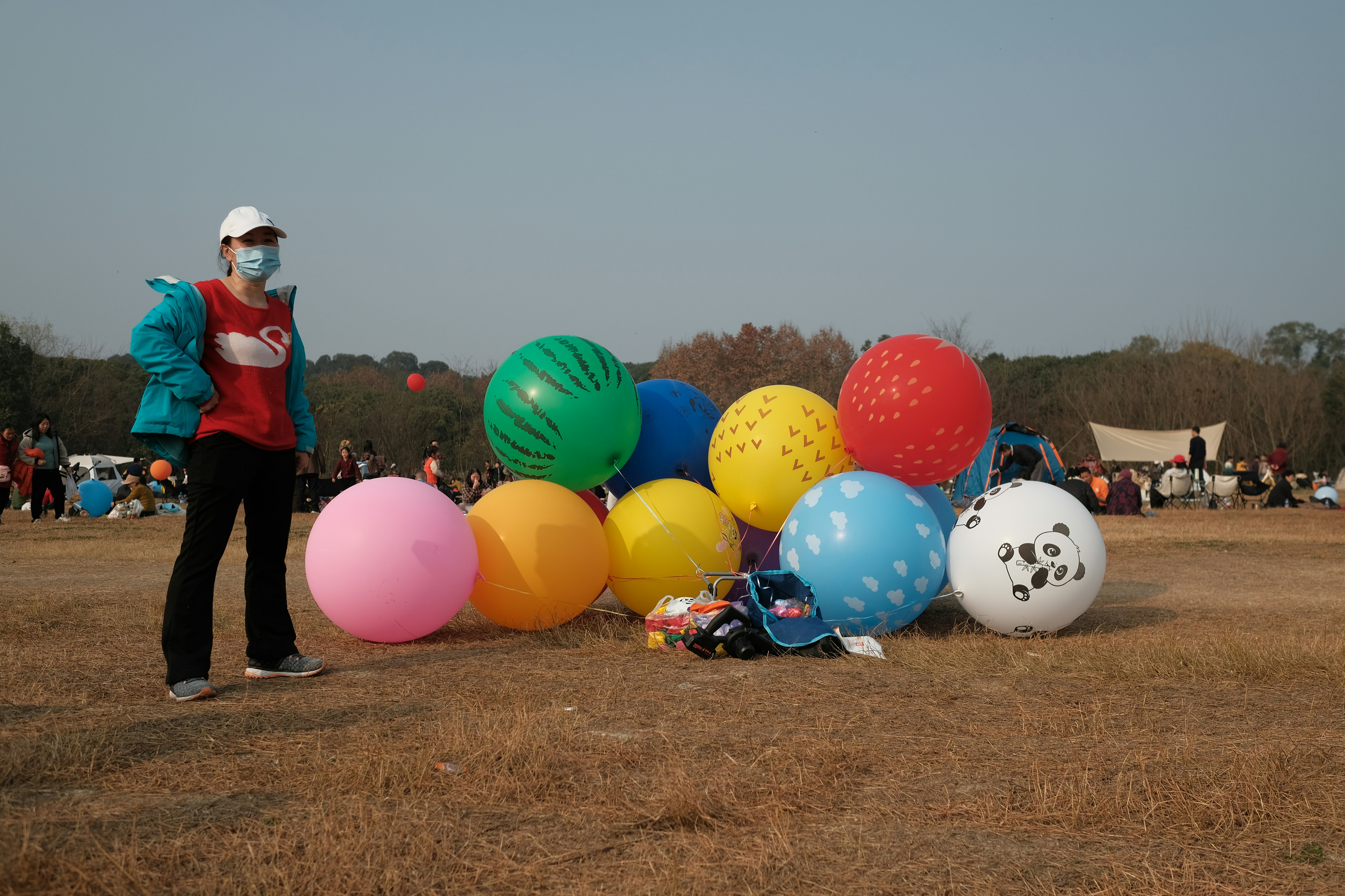 Person with colorful balloons on a grassy field