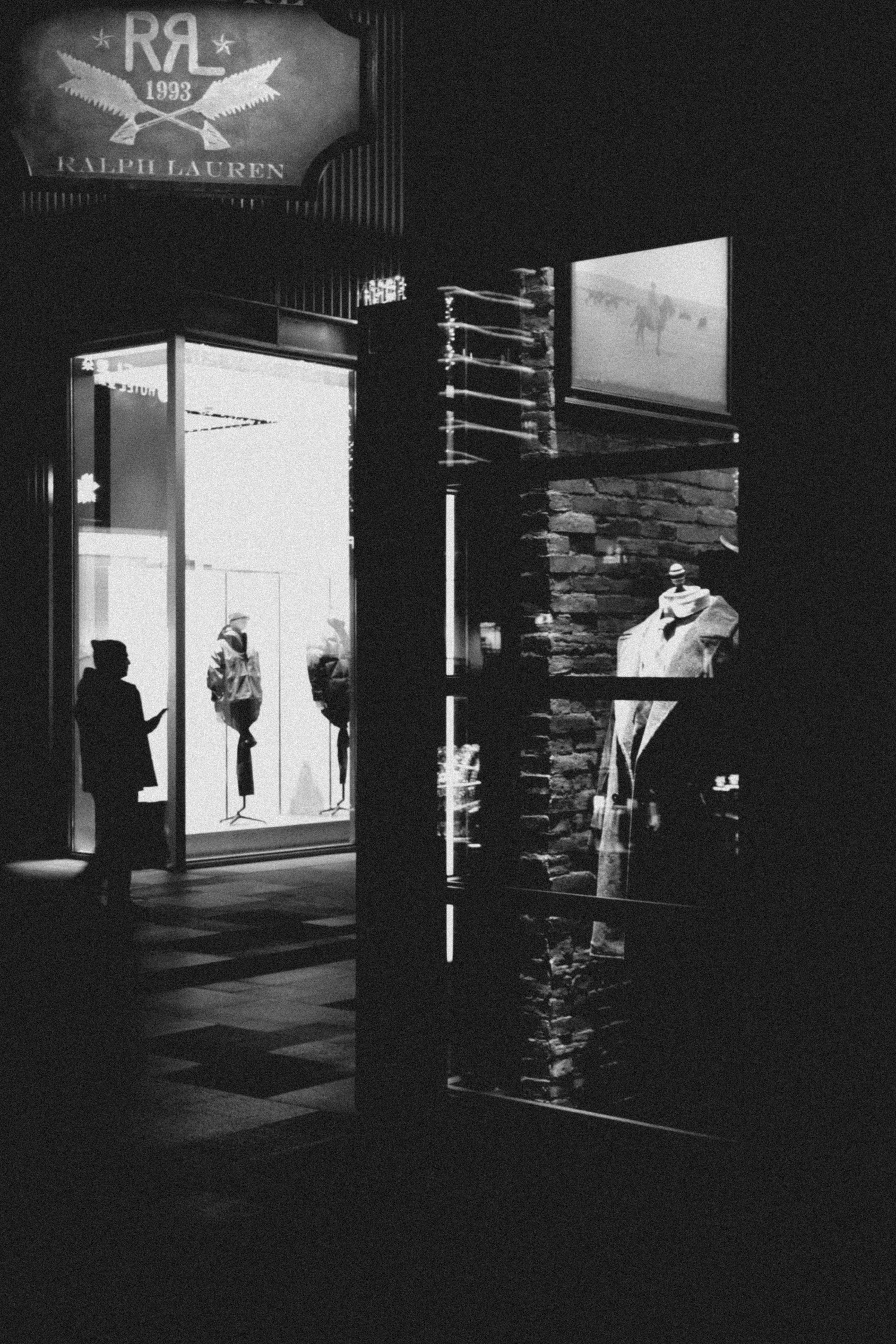 Storefront at night with mannequins in window display windows.