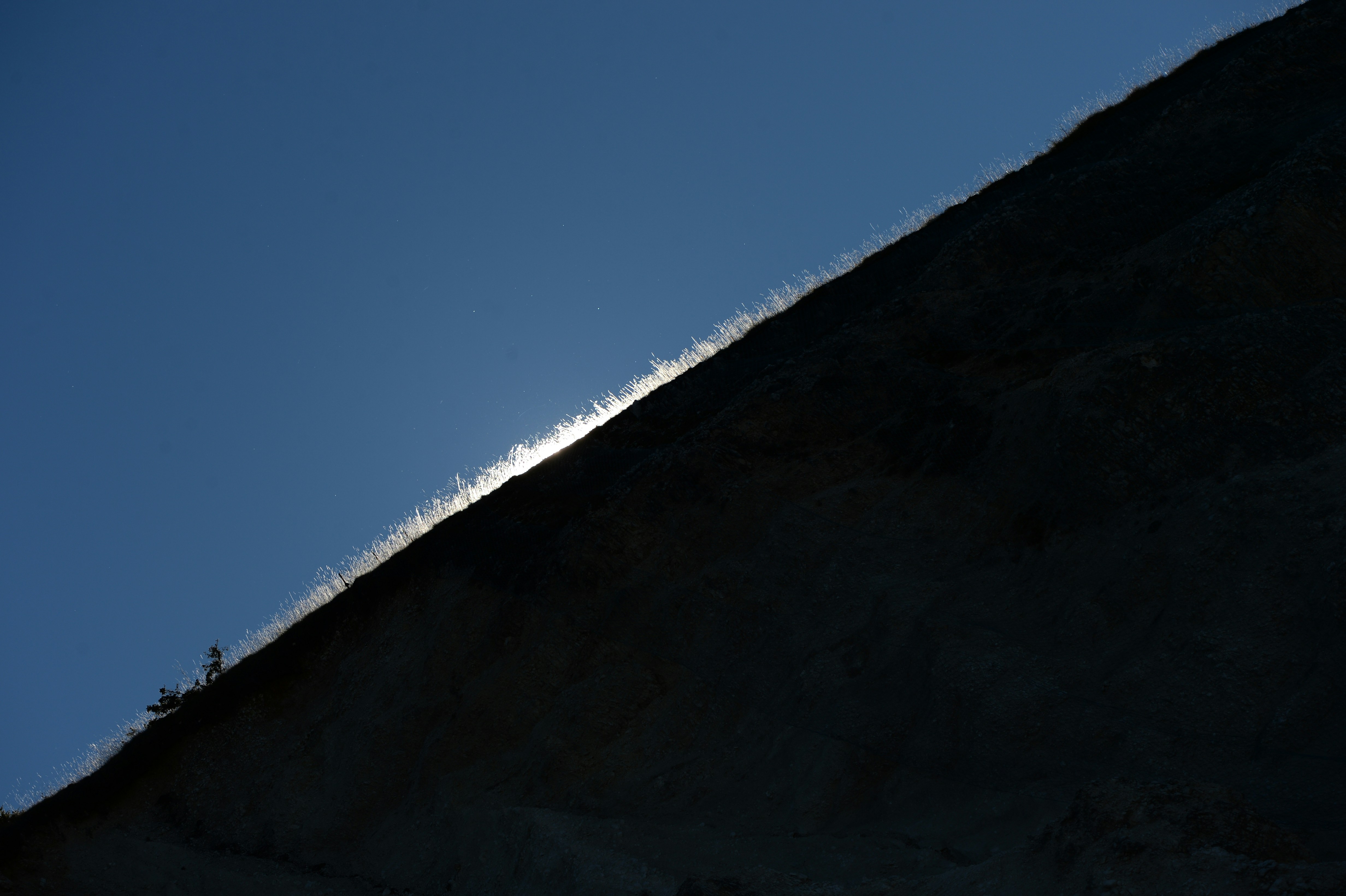 Sunlight glinting off a mountain ridge against blue sky