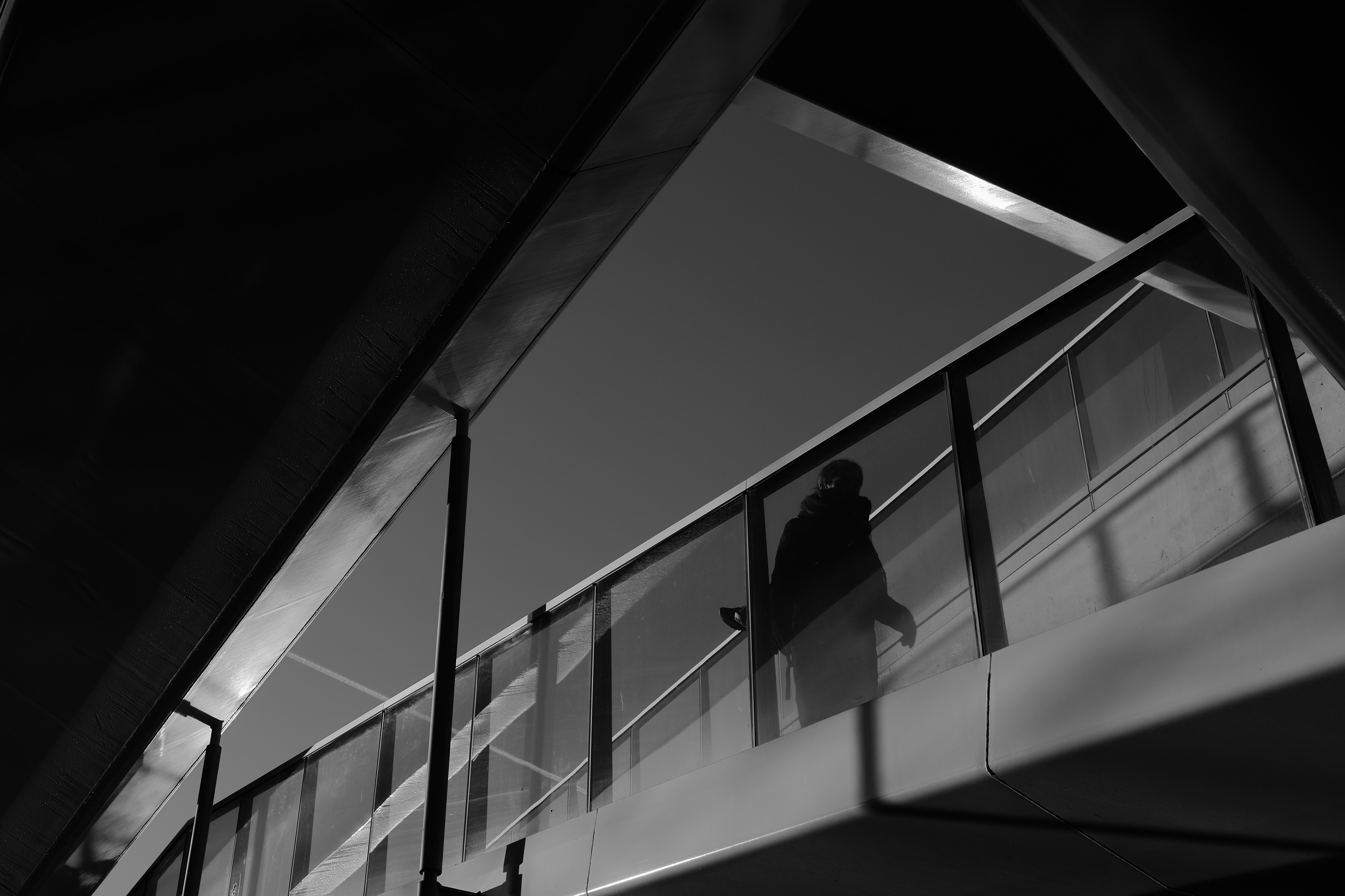 Silhouette of a person walking on a modern walkway