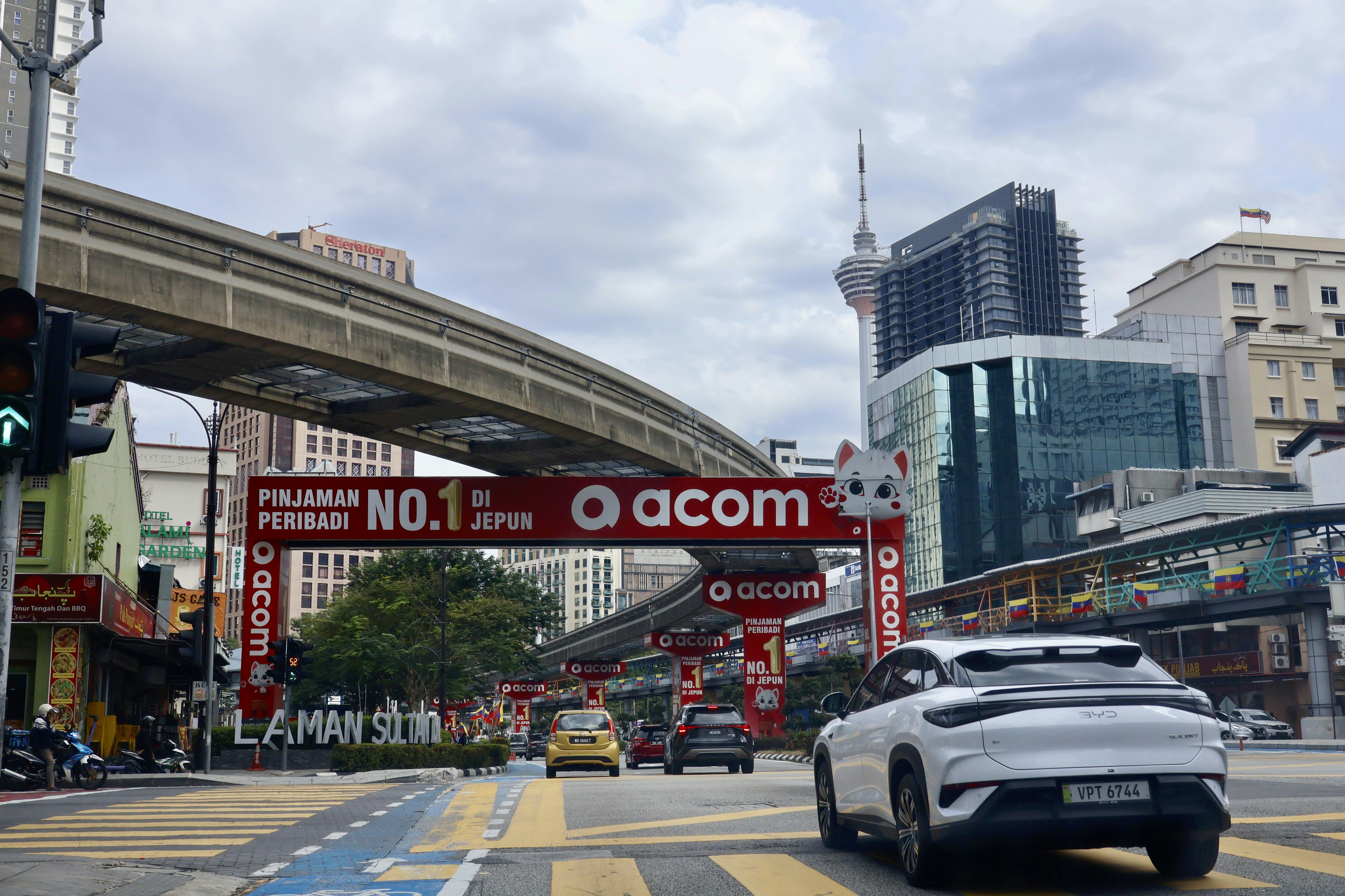 City street with monorail and cars under cloudy sky