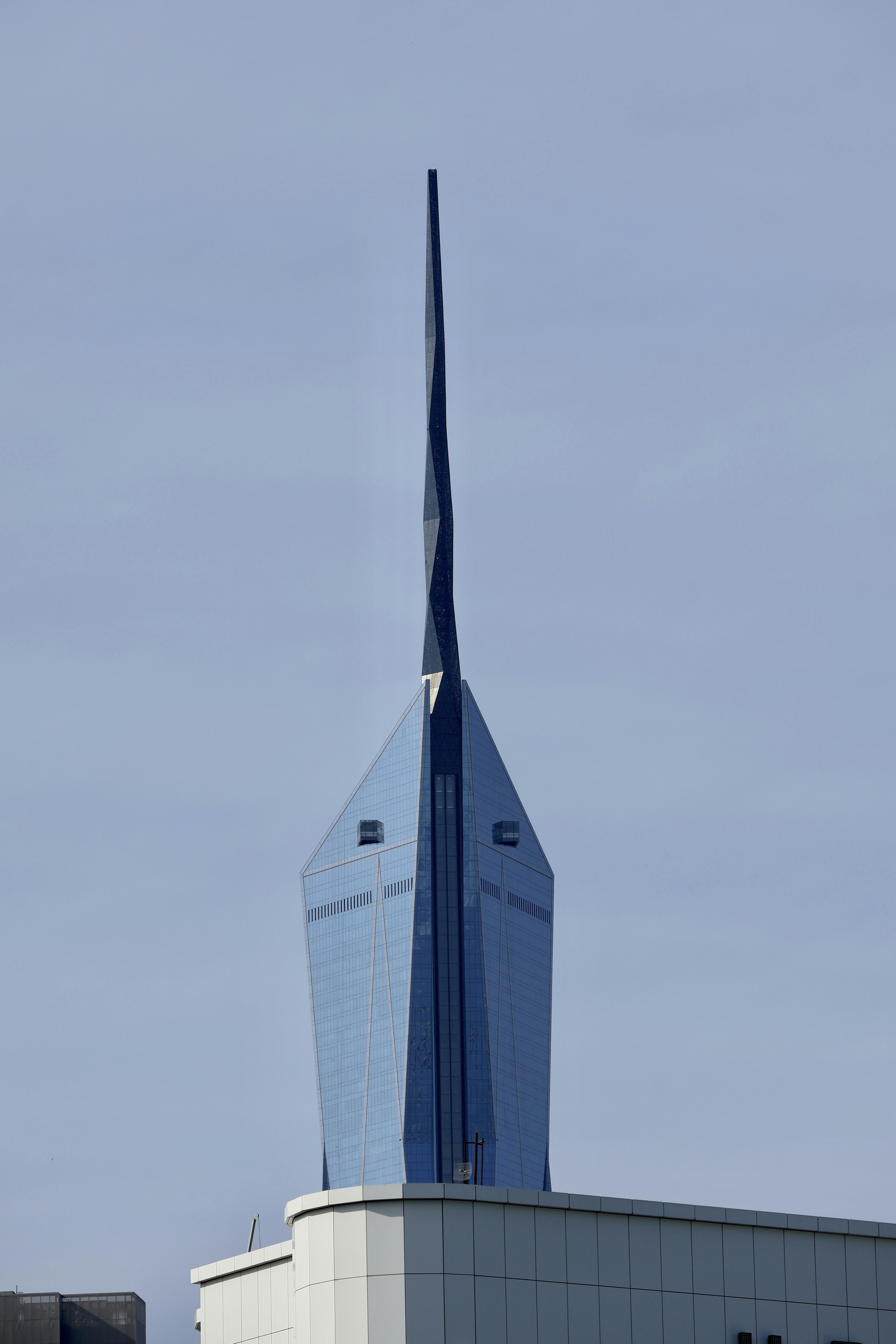 Modern skyscraper with a unique spire against blue sky
