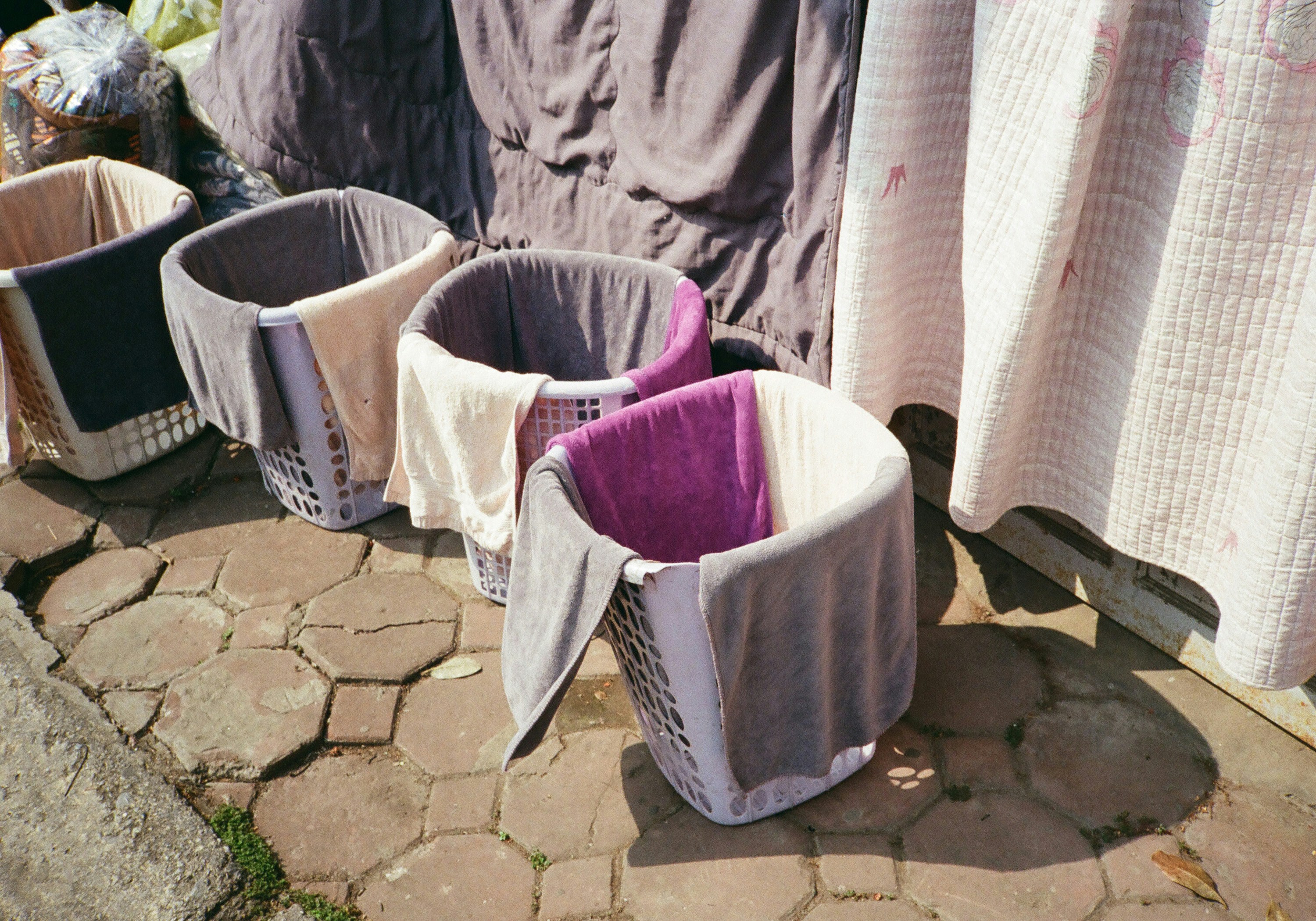 Four laundry baskets with clothes on pavement