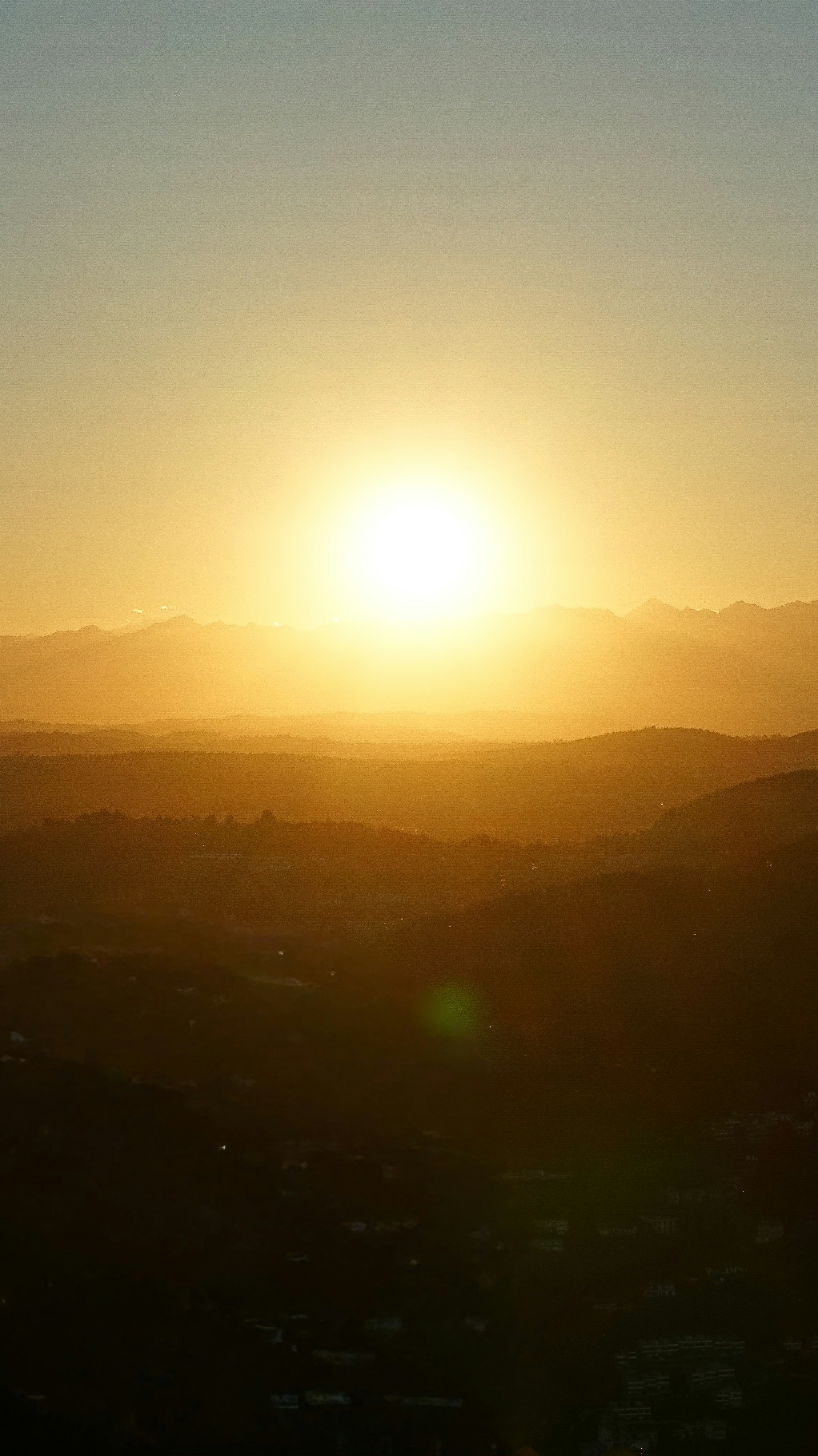 Golden sun setting over rolling hills at dusk