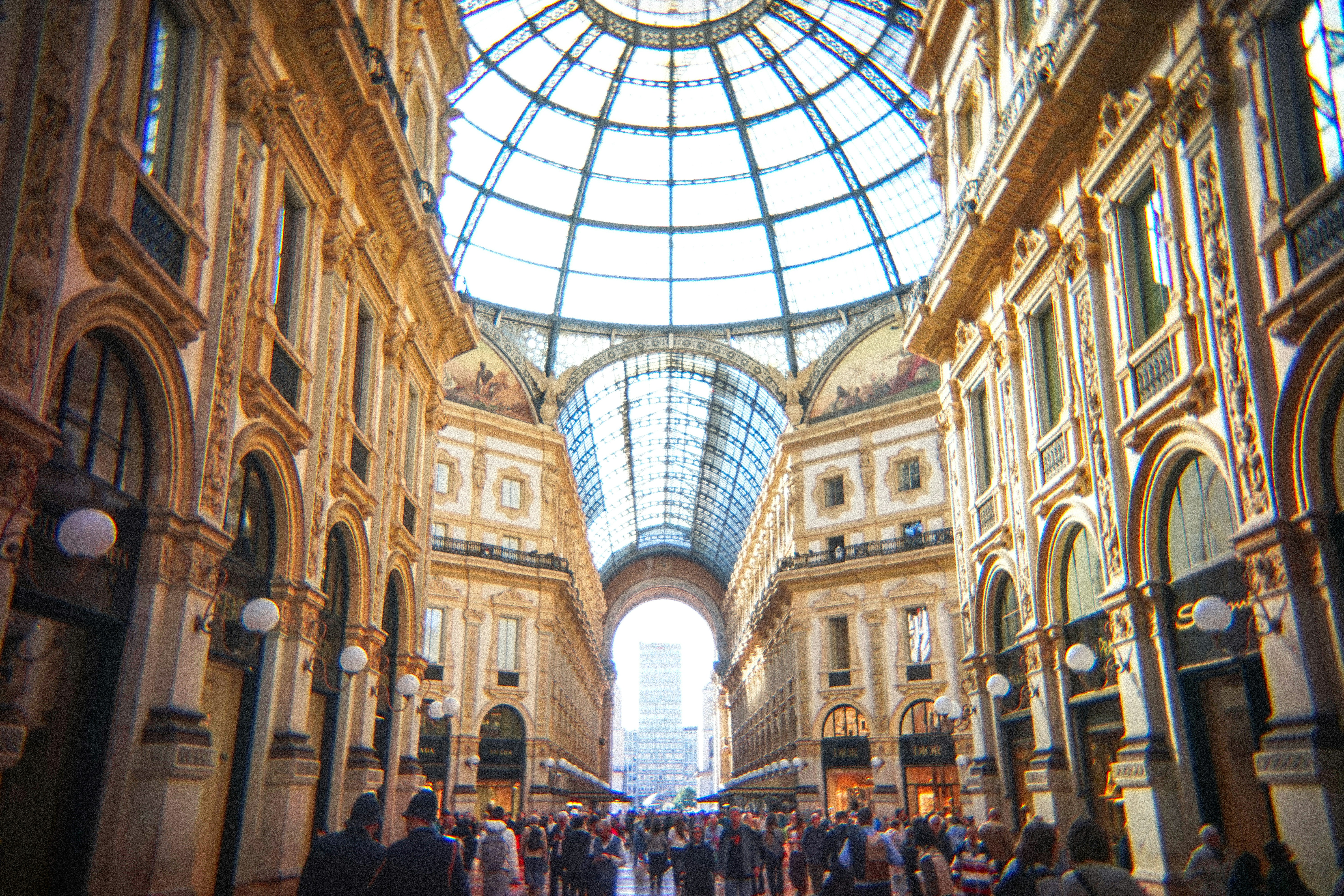 People walking through a grand, ornate shopping arcade