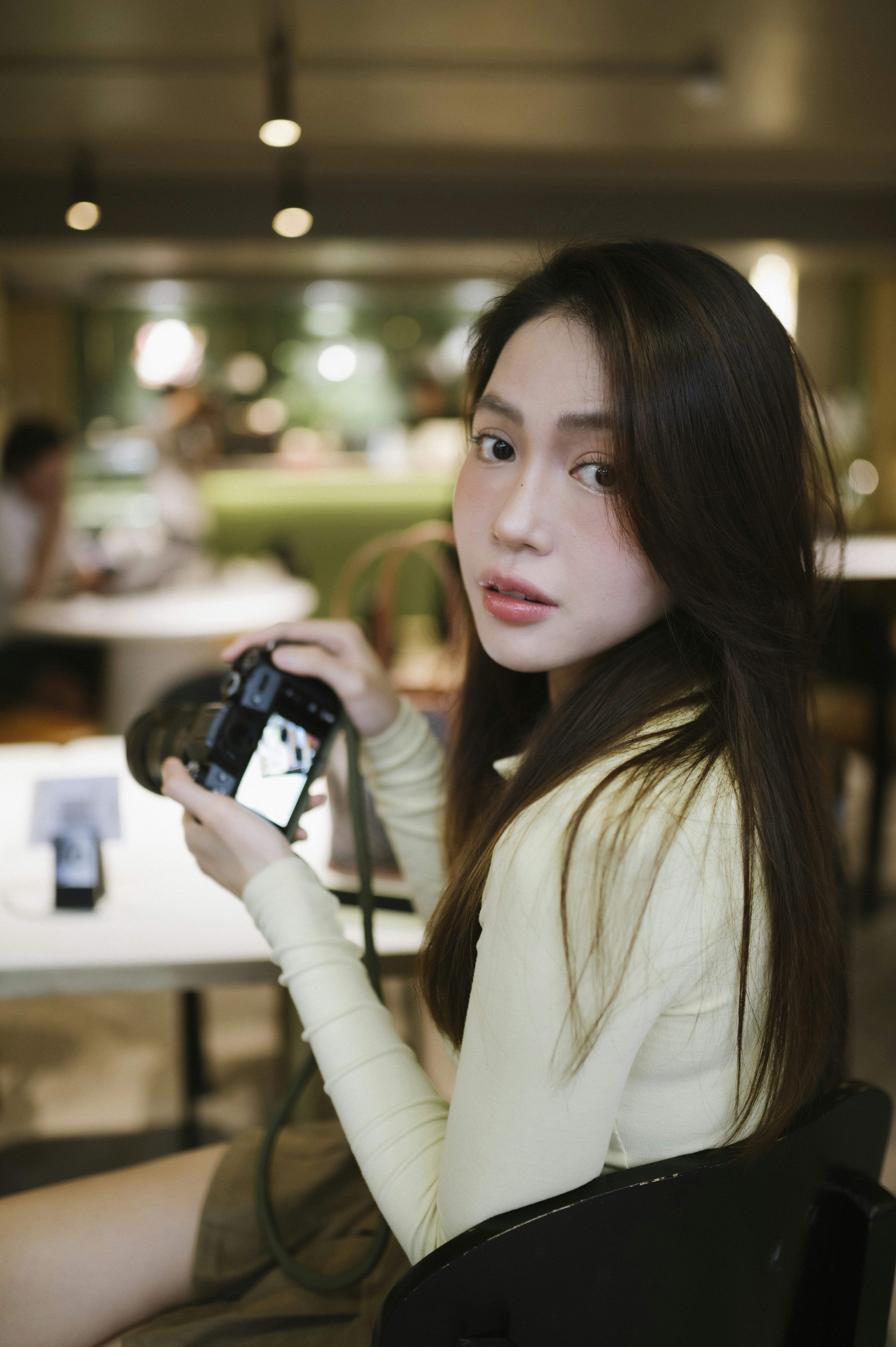 Young woman holding a camera in a cafe