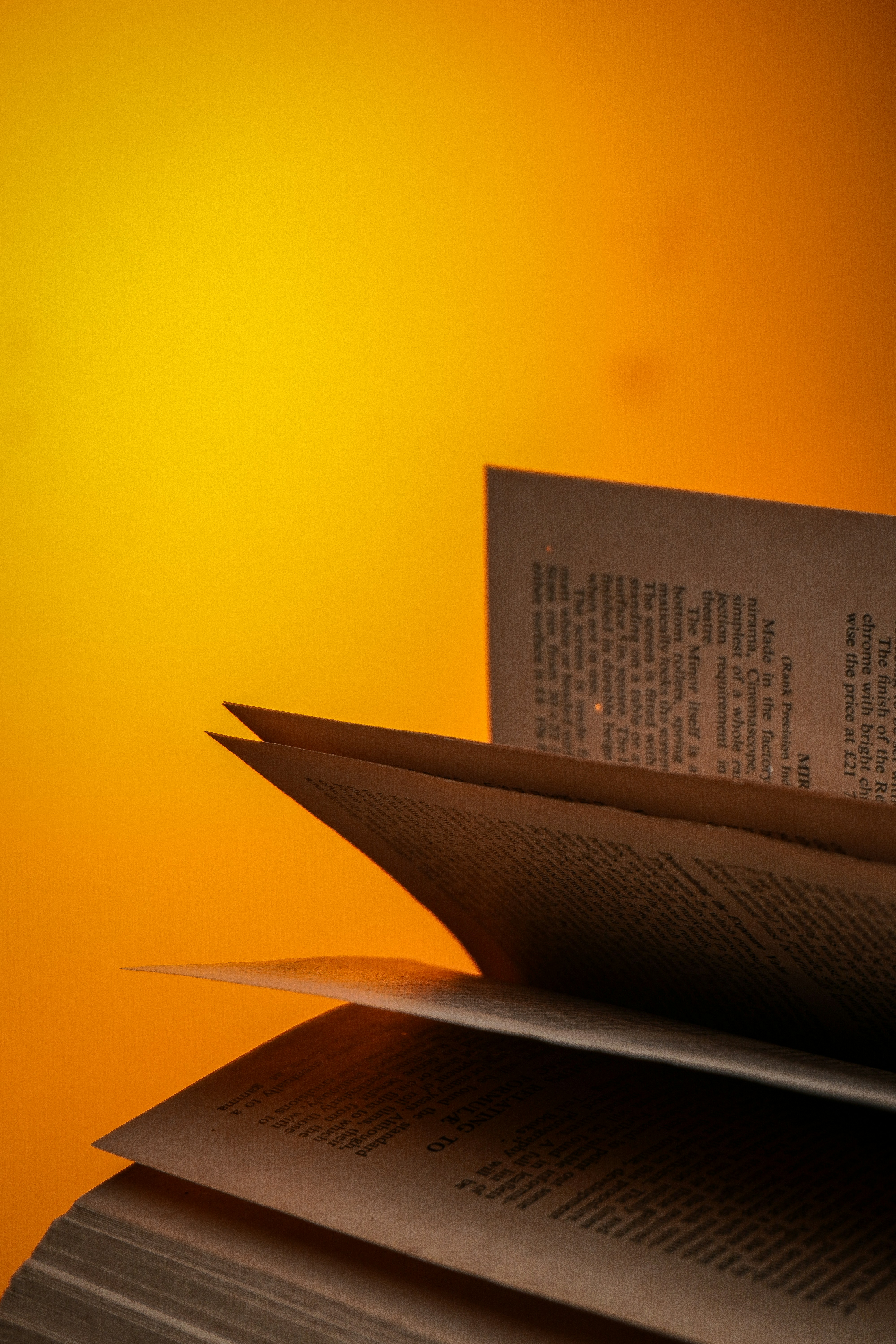 Um livro aberto com páginas virando sobre um fundo amarelo.